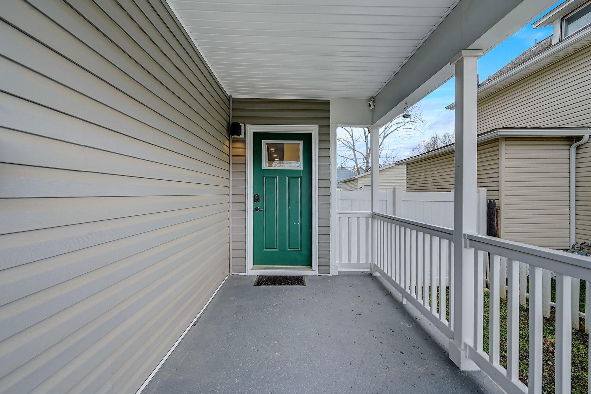 Covered porch with a green front door and white railings.