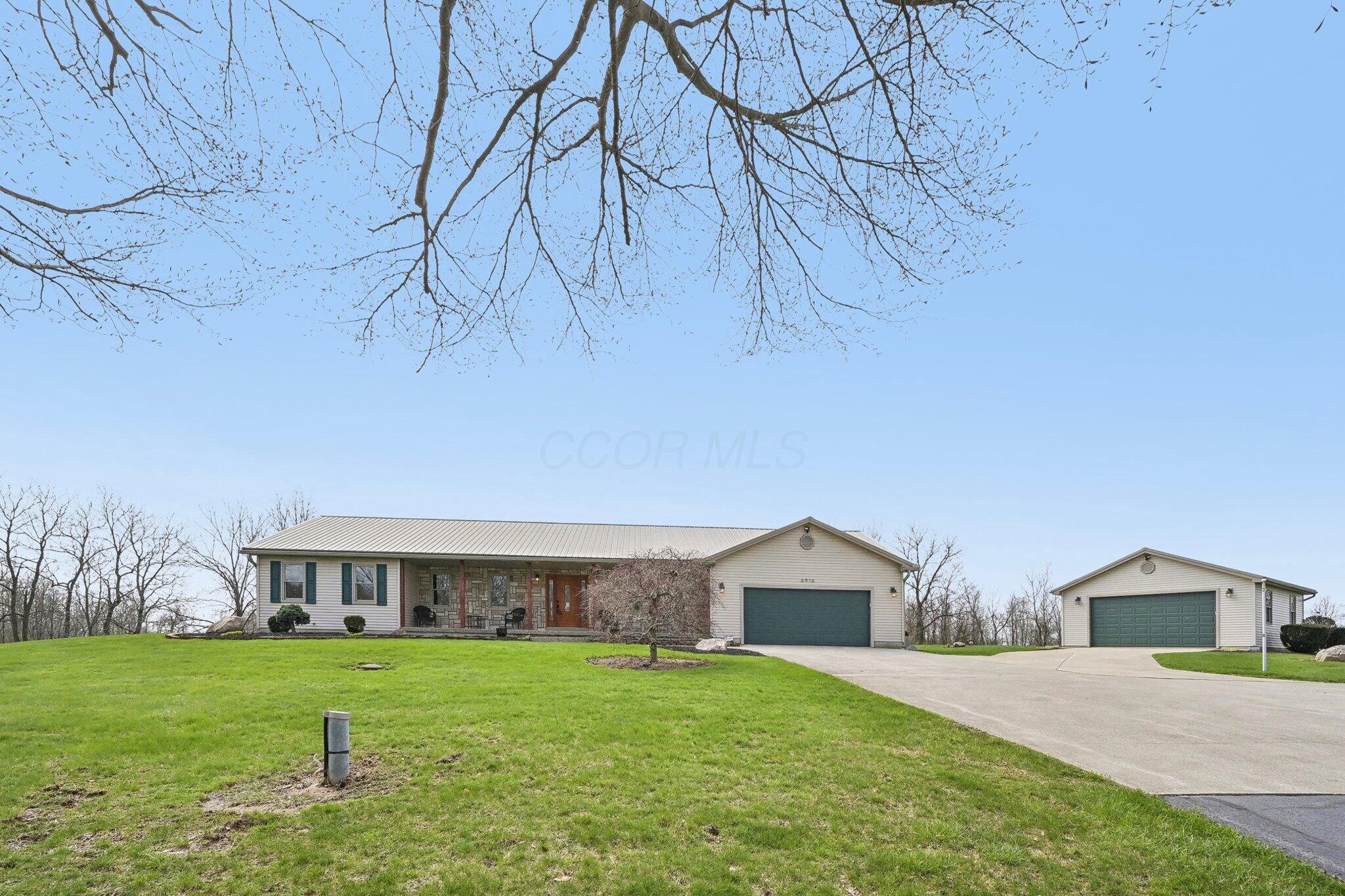Single-story home with a stone-accented porch, attached garage, and separate detached garage.