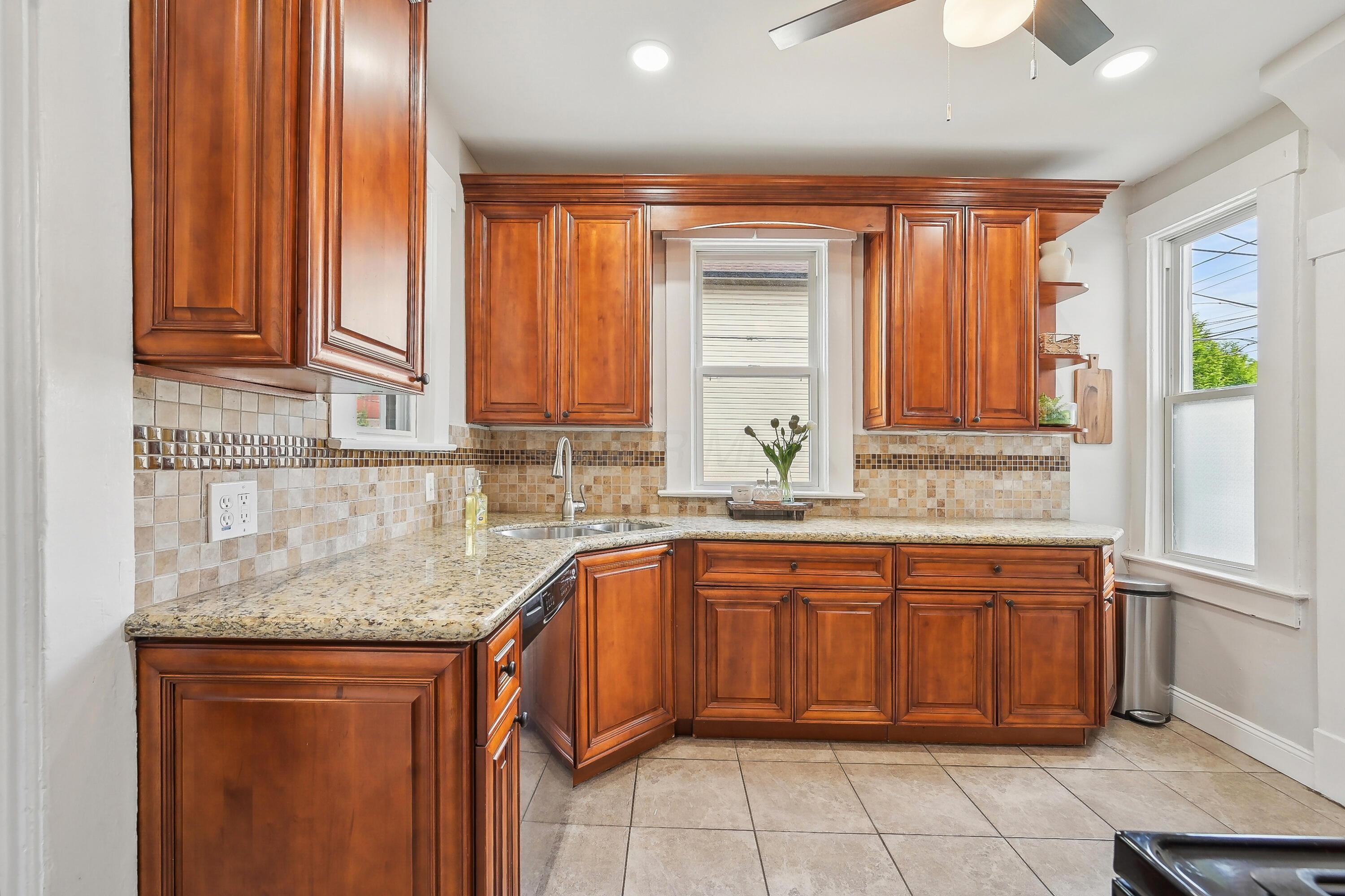 Kitchen with warm wood cabinets, granite countertops, and a tiled backsplash.