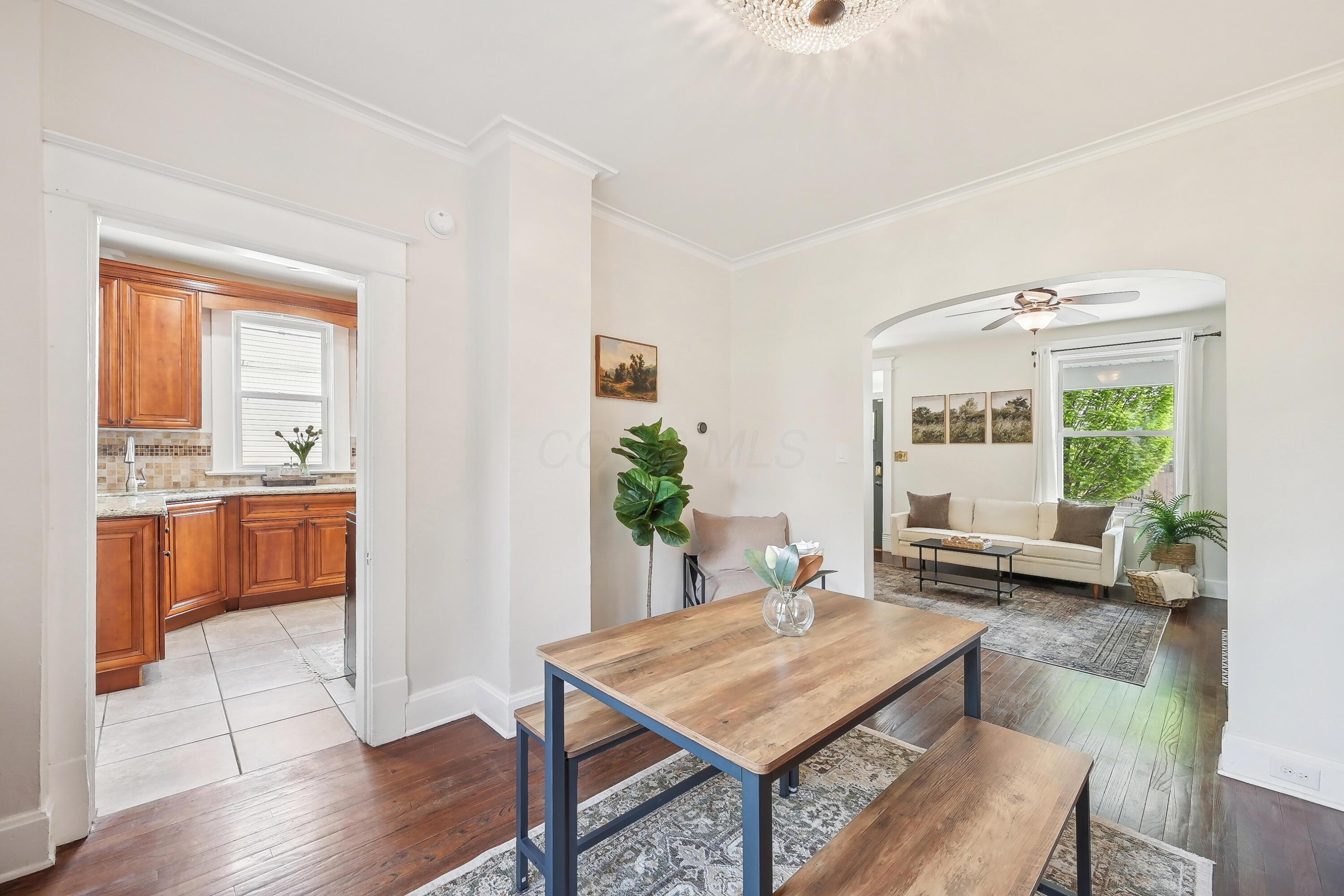 Dining room with a wood table, hardwood floors, and arched opening to the living room.
