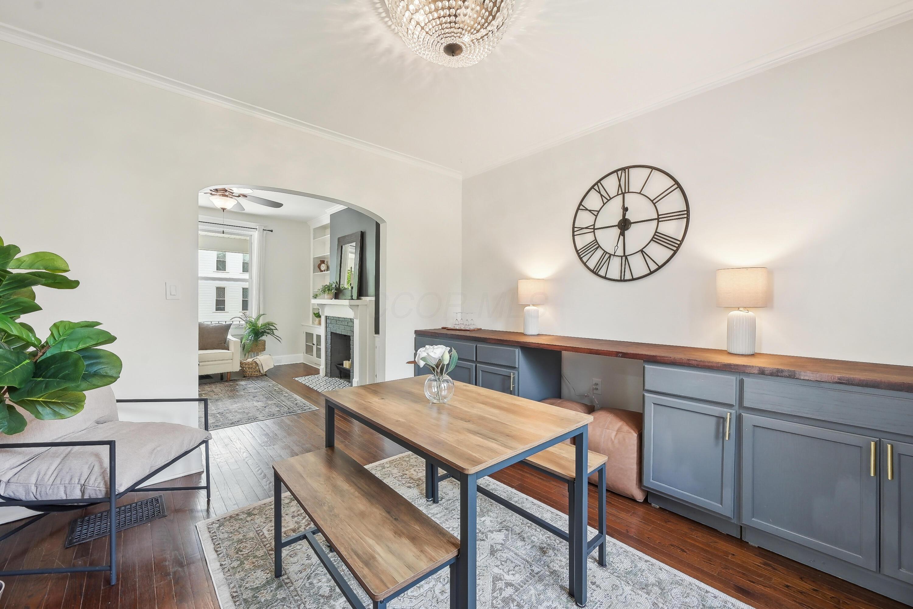 Dining room with blue built-in cabinets, a wood table, and an arched opening to the living room.