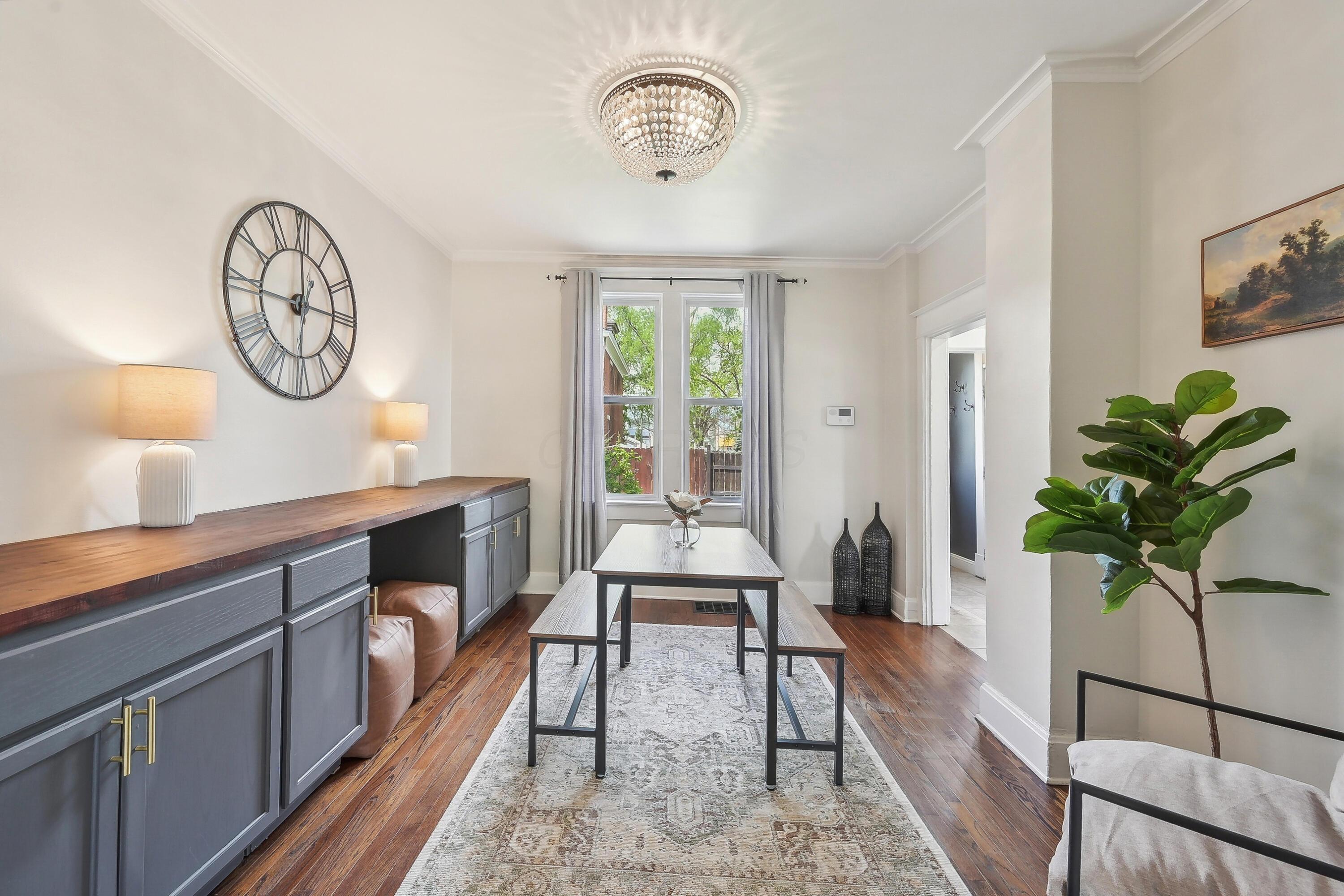 Dining room with gray built-in buffet, wood countertop, table and benches, hardwood floors, and a large window.