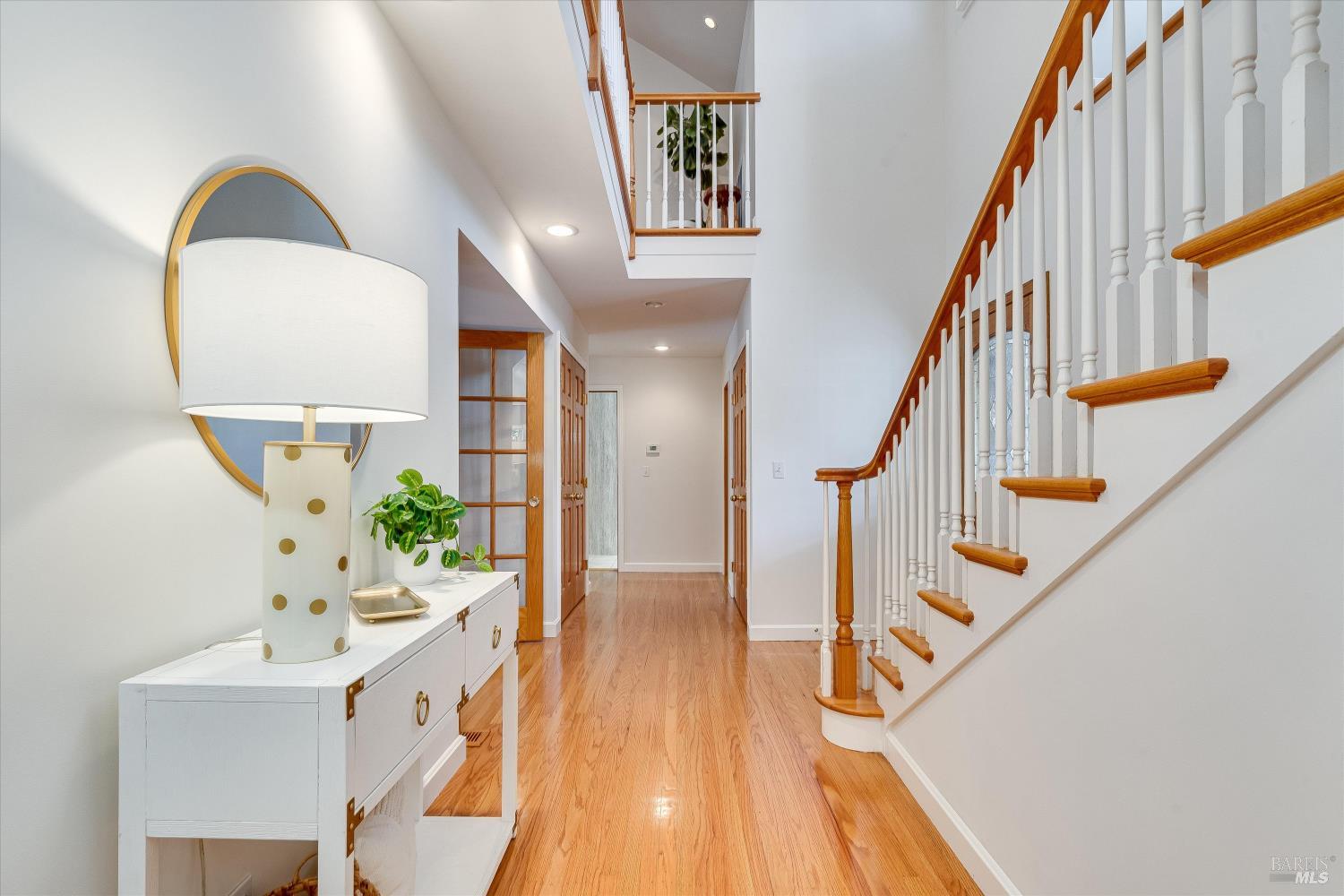 Entry hall with polished hardwood floors and a wood-trimmed staircase with white balusters.
