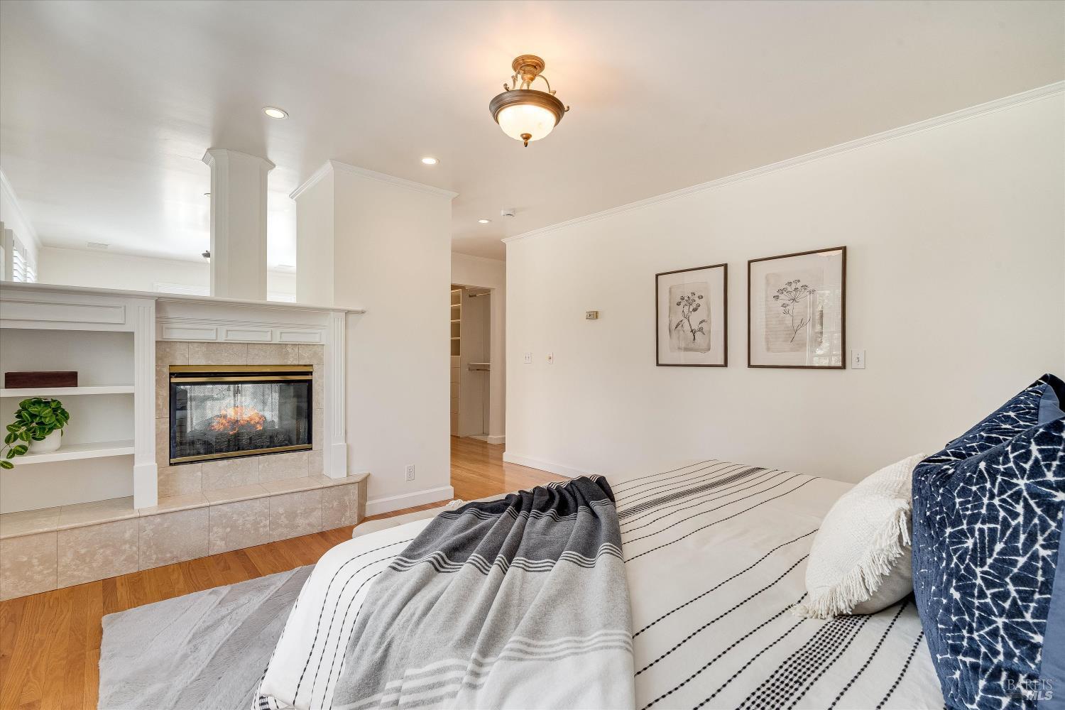Bedroom with a striped bed and tiled fireplace with built-in shelving.