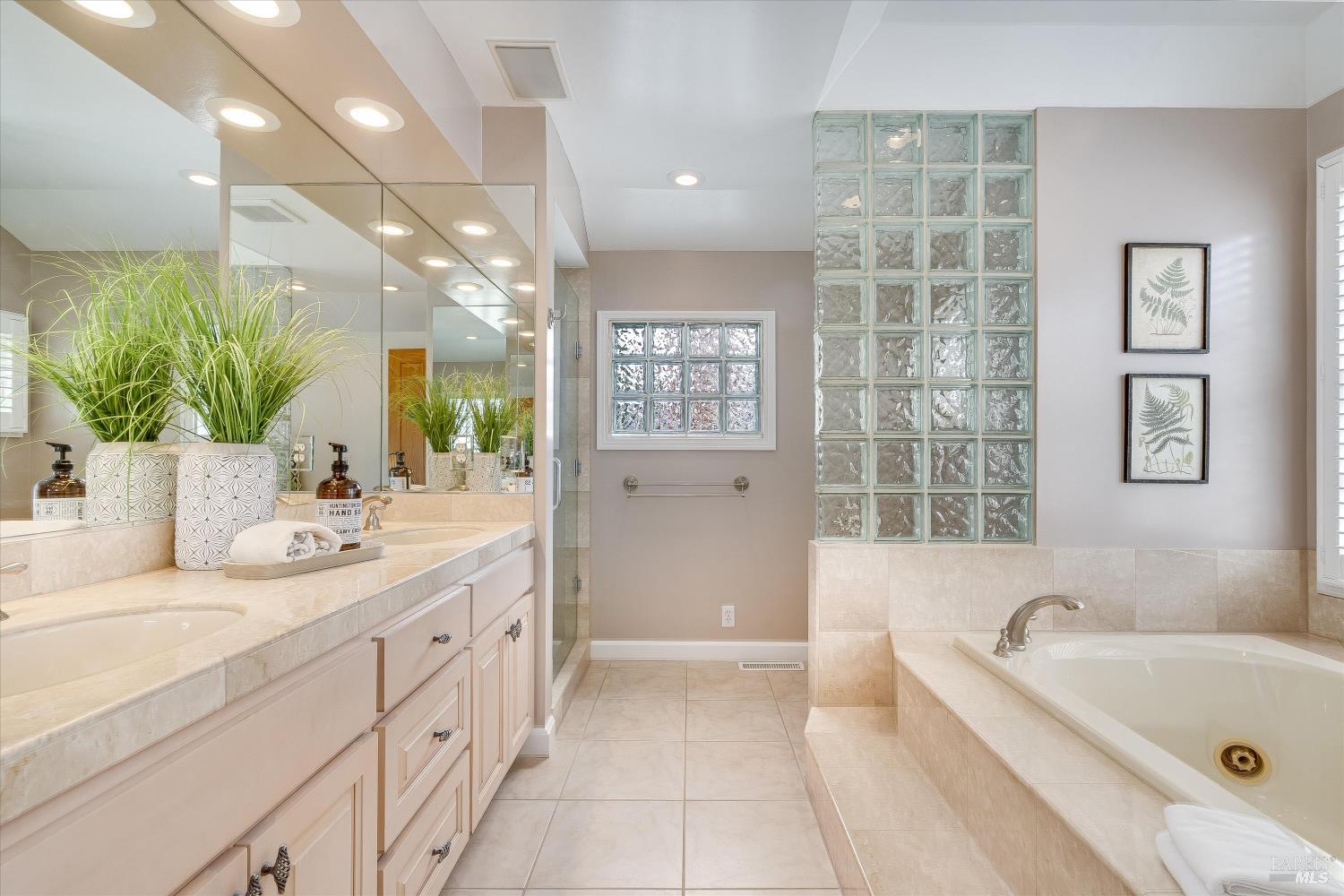 Spacious bathroom with a tiled vanity, built-in bathtub, and glass-block partition.