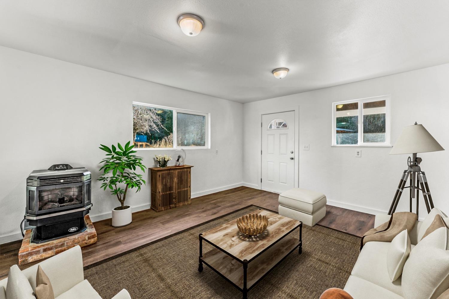 Staged living room with a freestanding wood stove, wood-look floors, and a central coffee table.