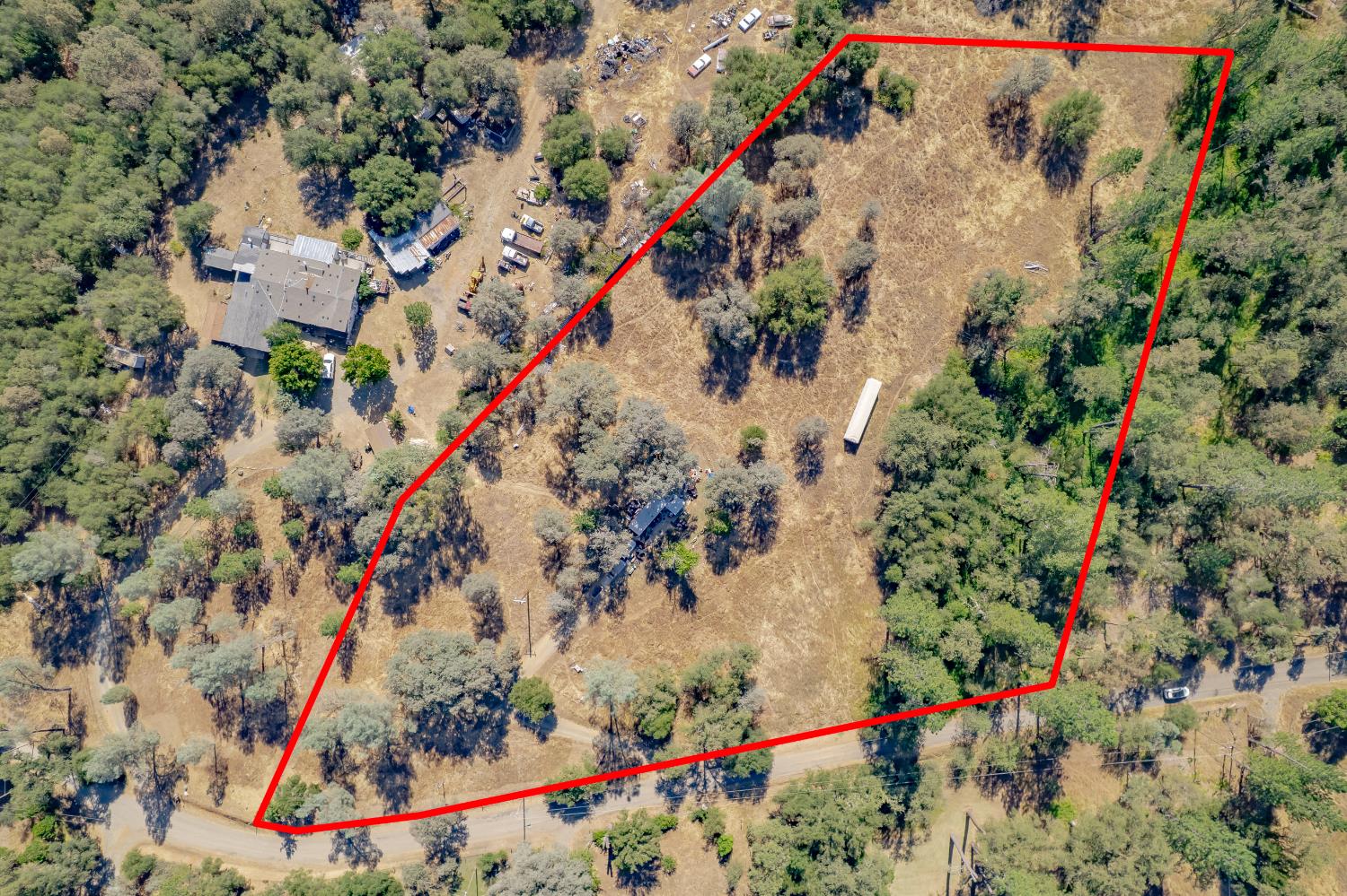 Aerial view of a wooded rural parcel outlined in red, with dry open land and roadside access.