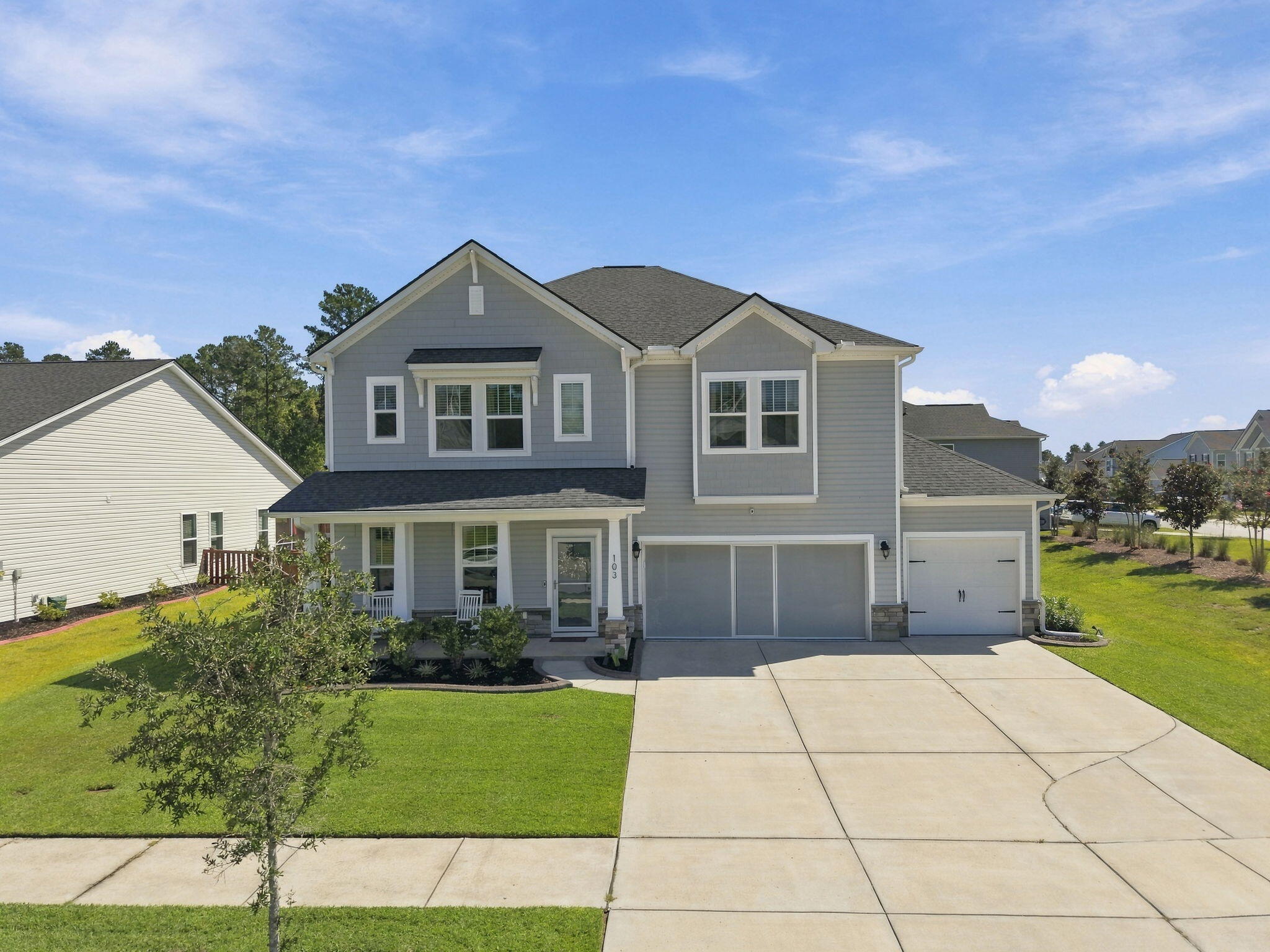 Two-story gray home with a covered porch, attached garage, and broad driveway.