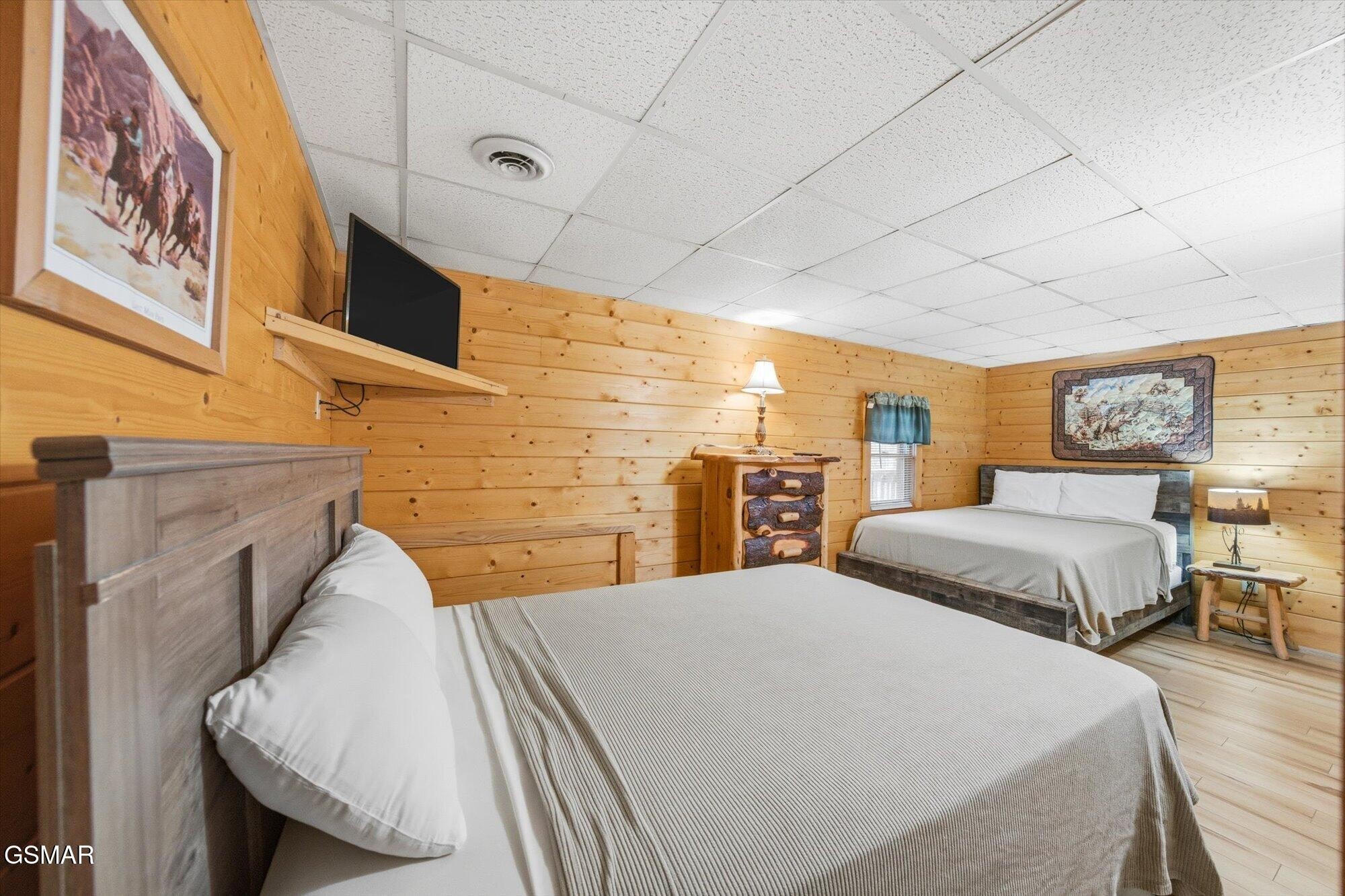 Bedroom with two beds, knotty-pine walls, and rustic wood furnishings.