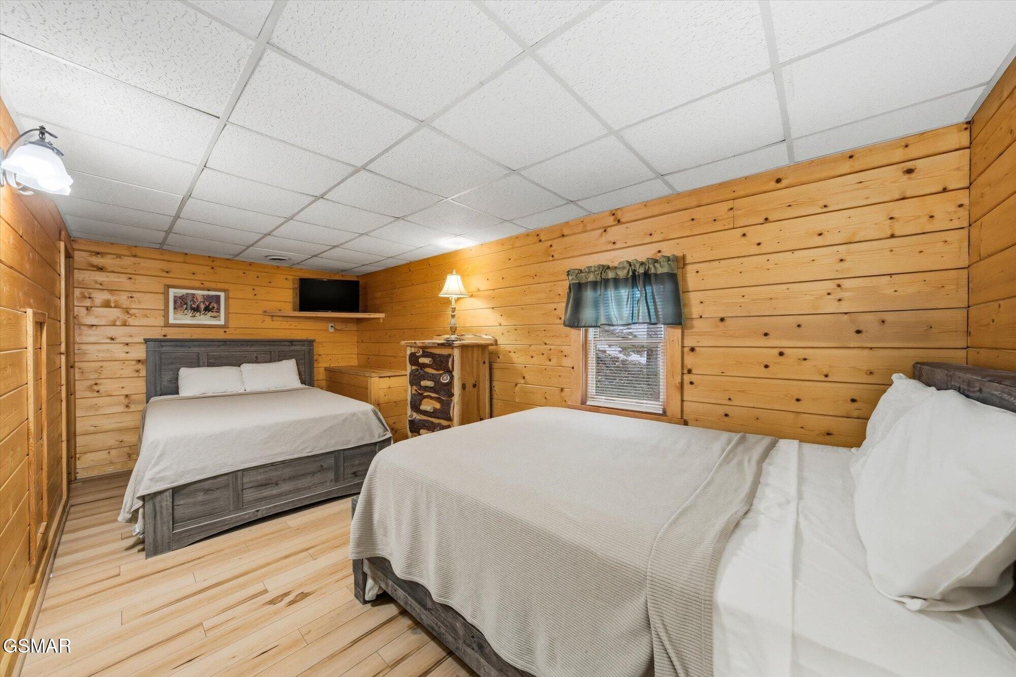 Bedroom with two beds, warm wood plank walls, and blue curtains.