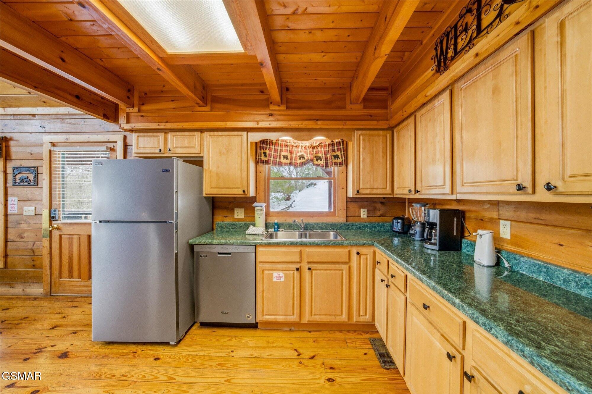 Cabin kitchen with wood cabinets, green countertops, and snow visible through the window.