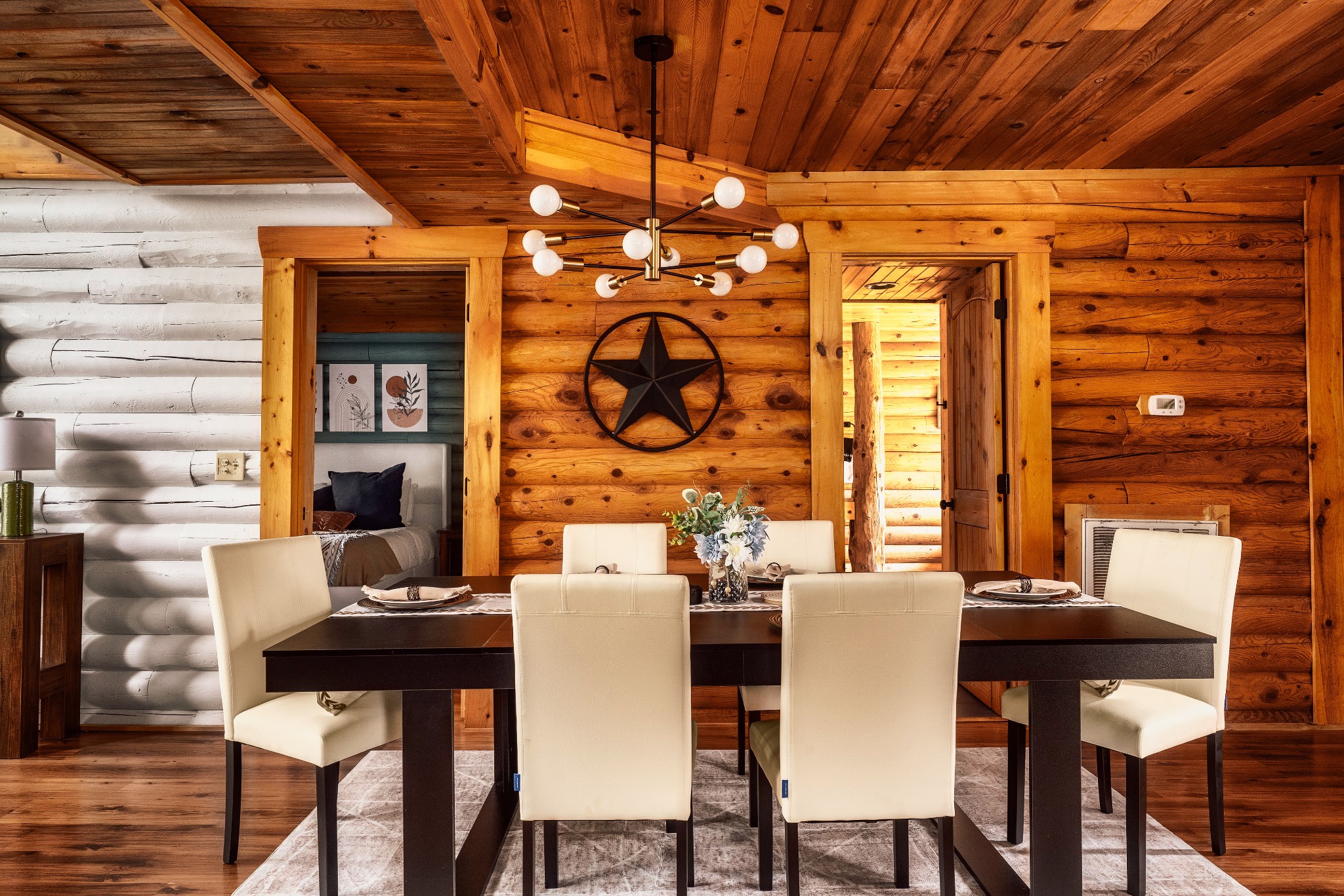 Log cabin dining room with a dark table, cream chairs, and a modern globe chandelier.