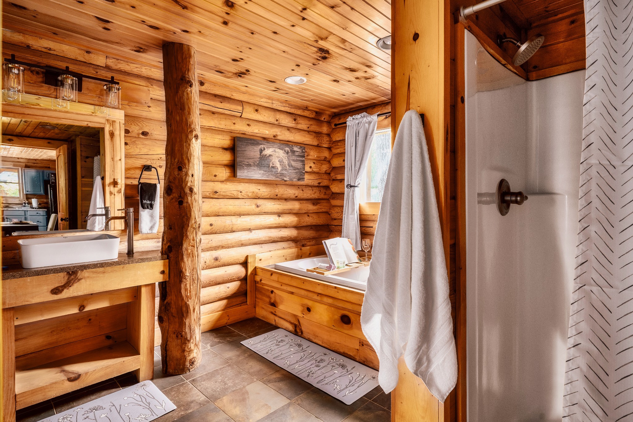 Rustic log-cabin bathroom with a soaking tub, vessel sink, and walk-in shower.
