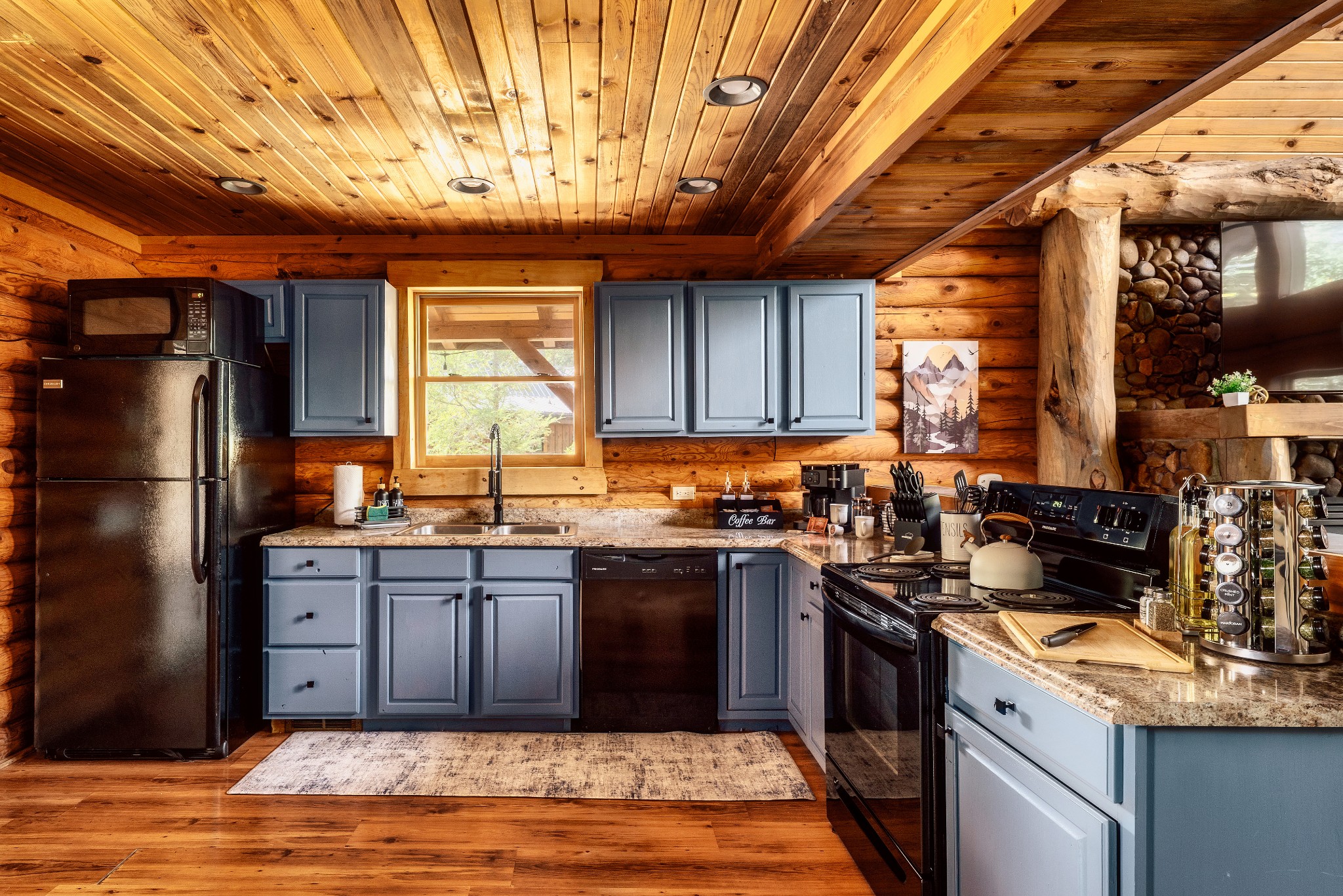 Log-cabin kitchen with blue-gray cabinets, granite counters, and a coffee bar.