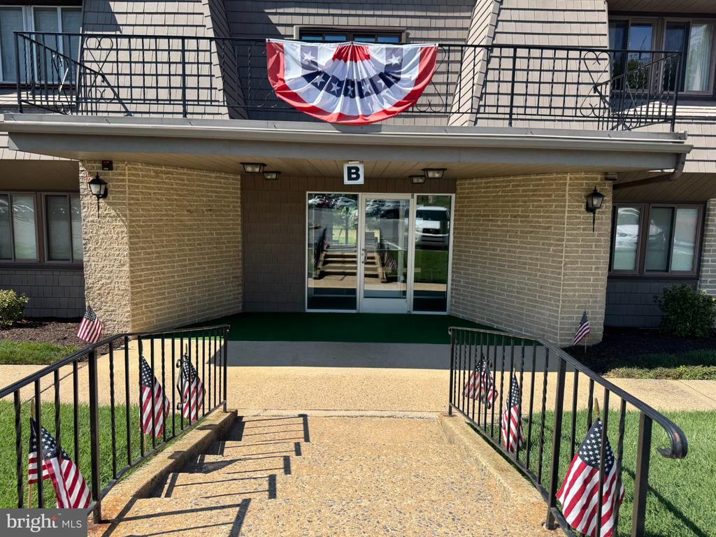 Residential building entrance marked B, decorated with American flags and red, white, and blue bunting.