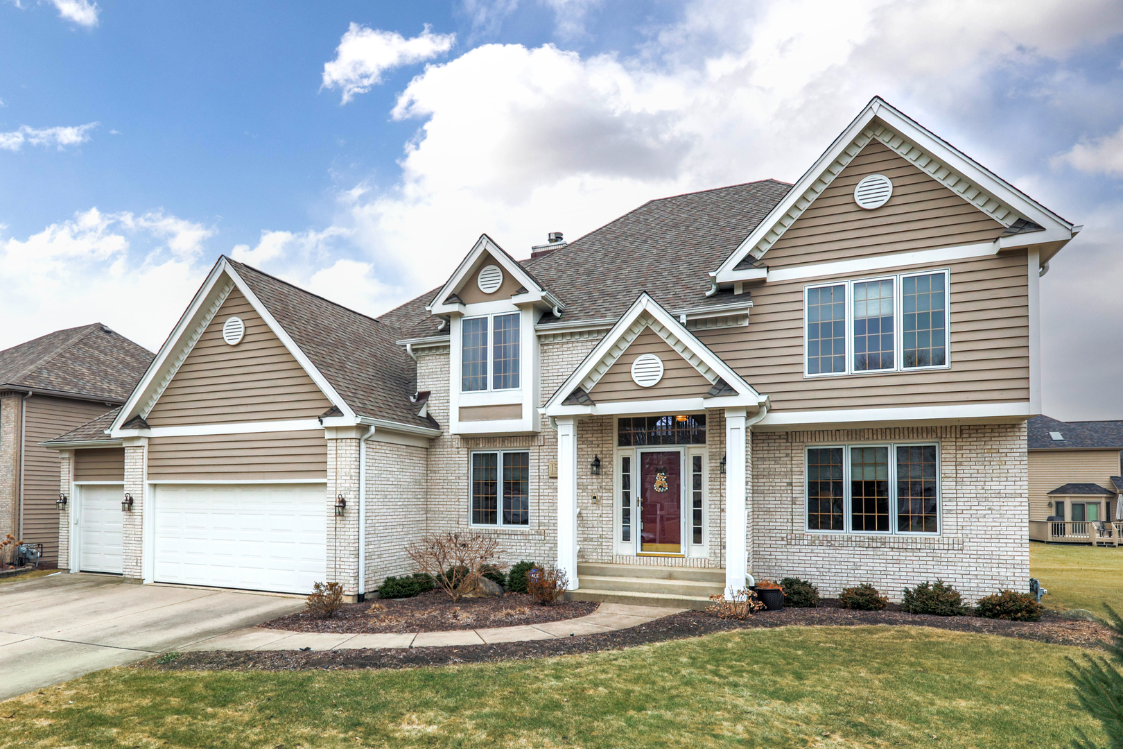 Two-story brick-and-siding home with multiple gables, a covered entry, and an attached two-car garage.
