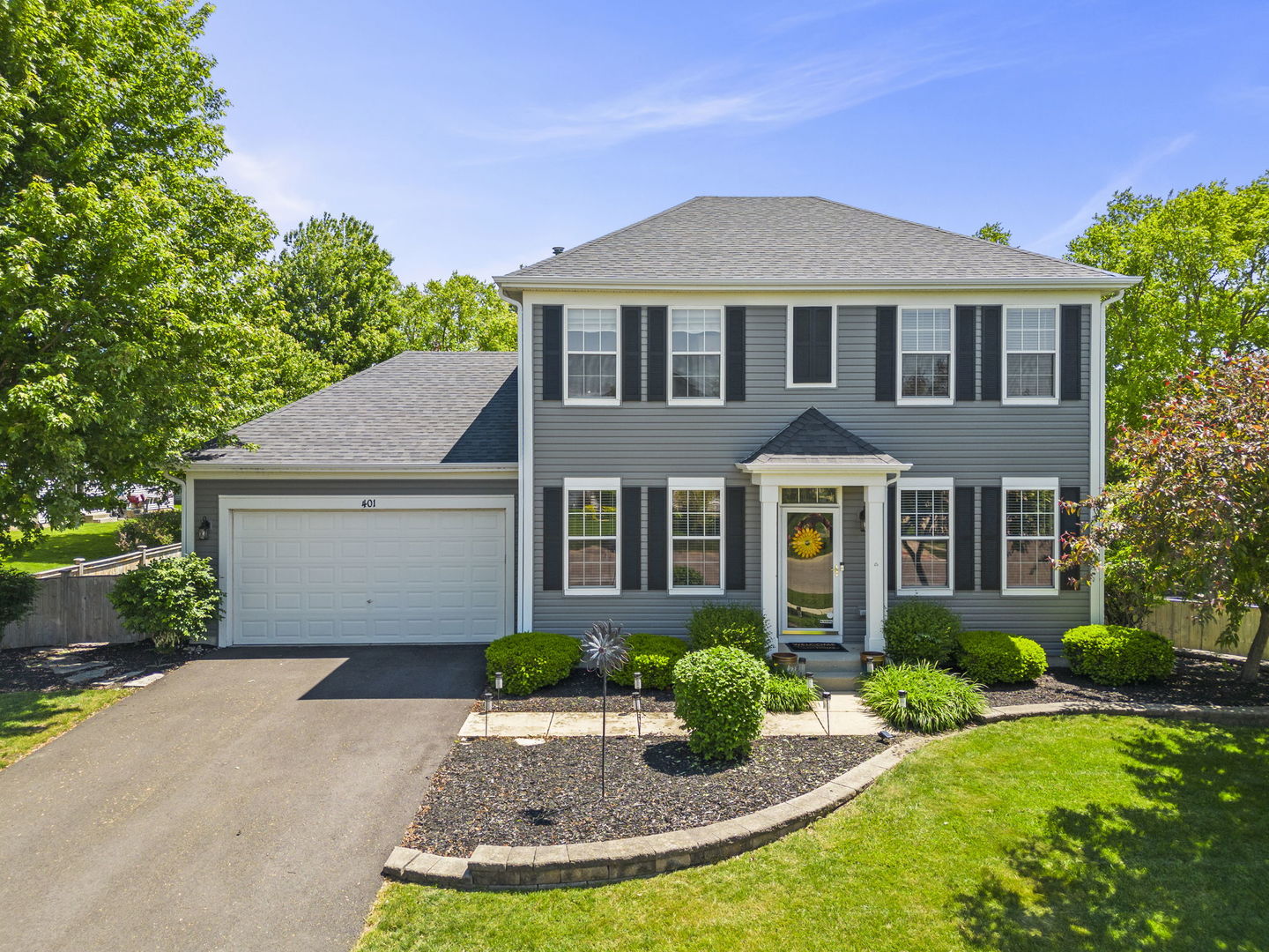 Two-story gray house with black shutters, attached garage marked 401, and landscaped front yard.