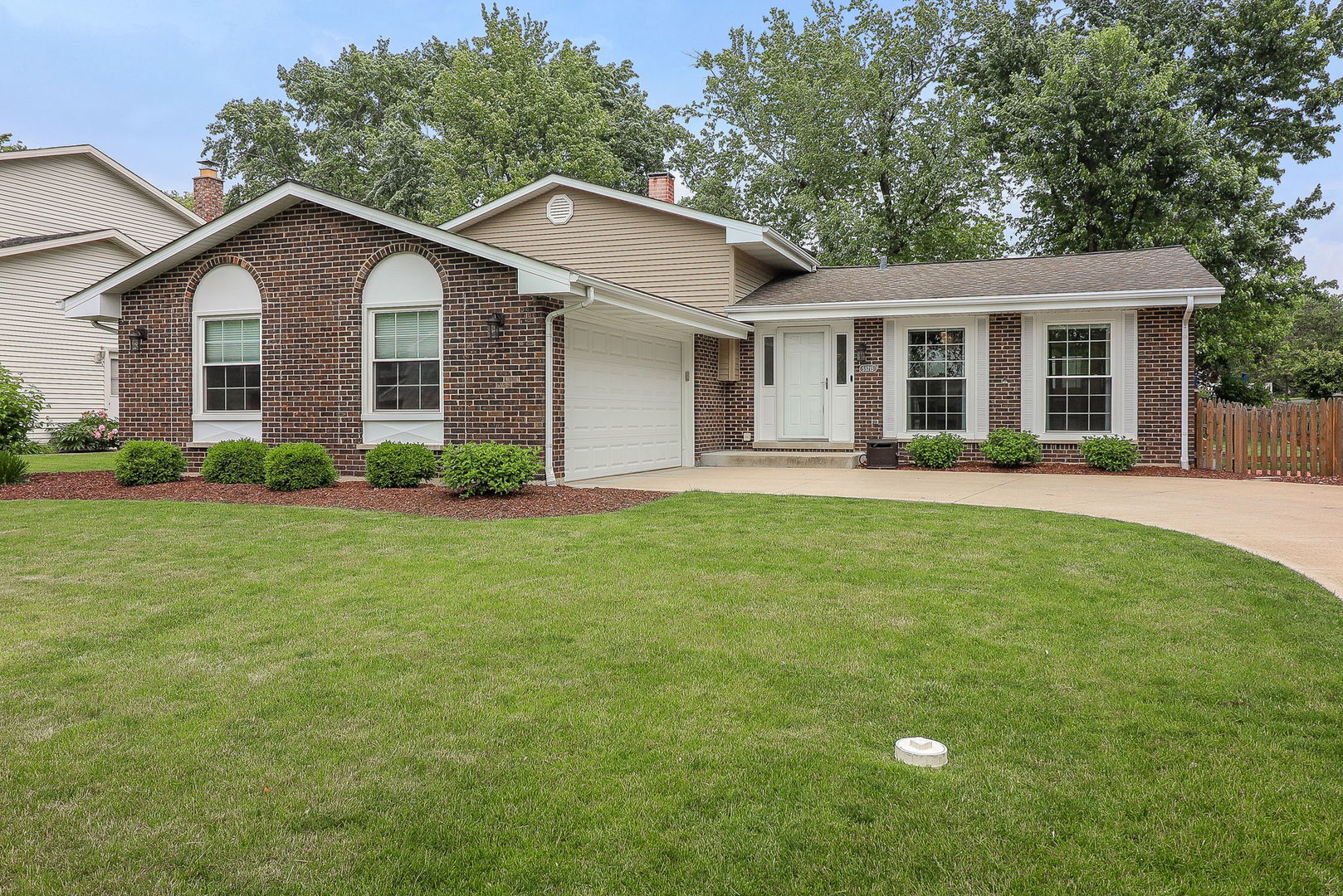Brick-front home with arched windows, attached garage, and a broad green lawn.