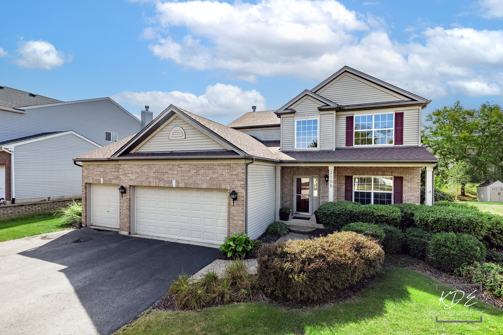 Two-story brick-and-siding home with a two-car garage and landscaped front yard.