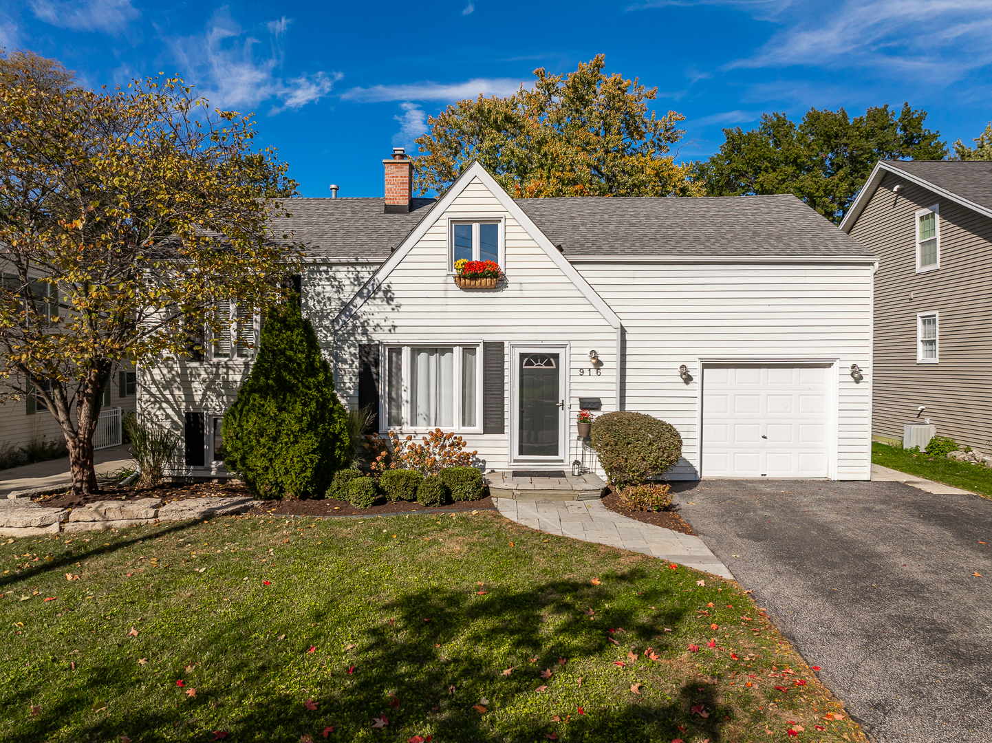 White-sided home with a steep front gable, flower boxes, and an attached garage.