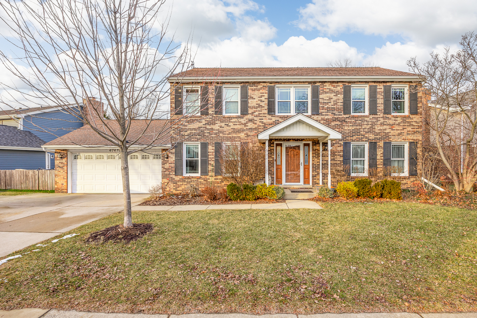 Two-story brick home with an attached garage and white covered entry.