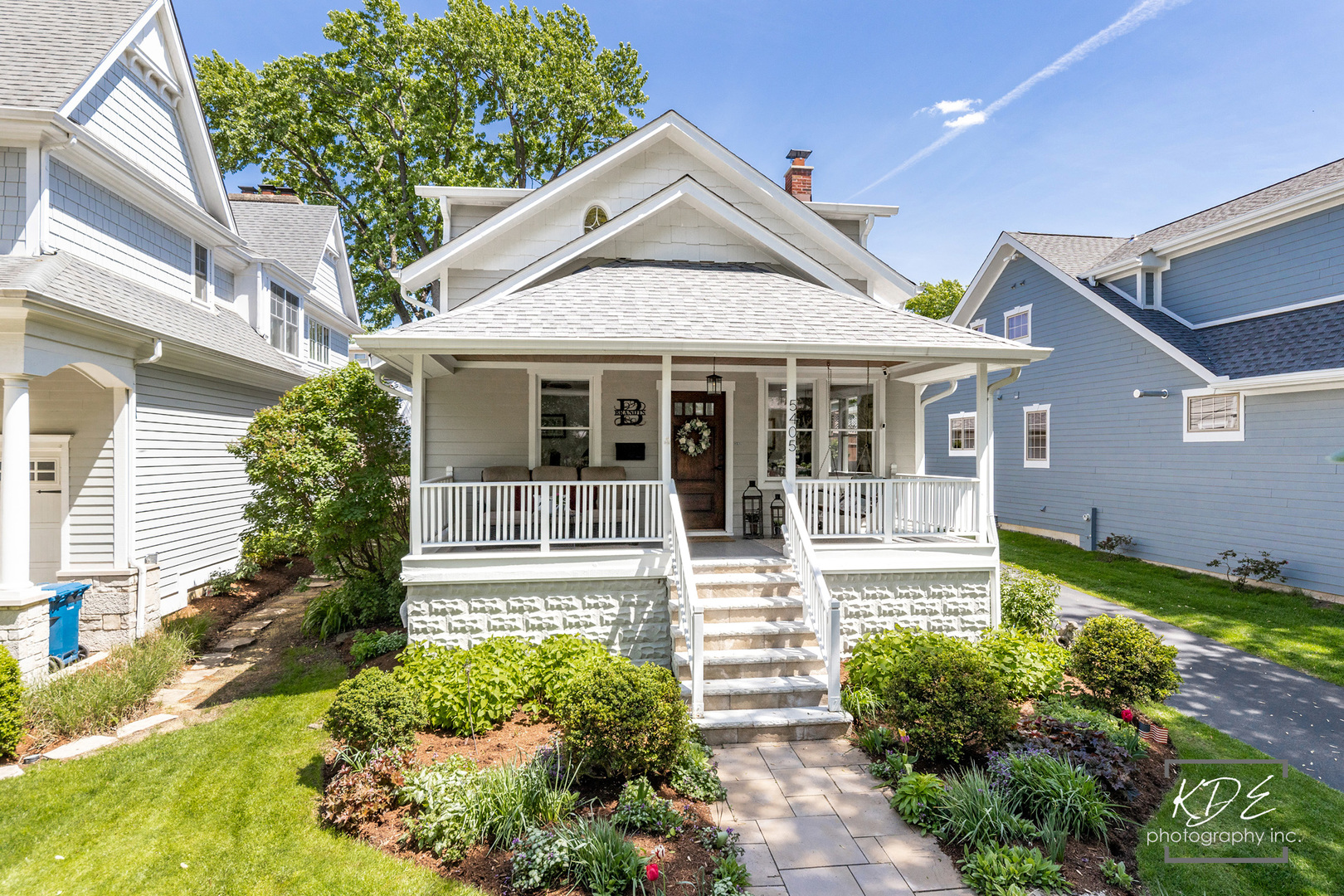 Gray house with a covered porch, stone foundation, and landscaped front garden.