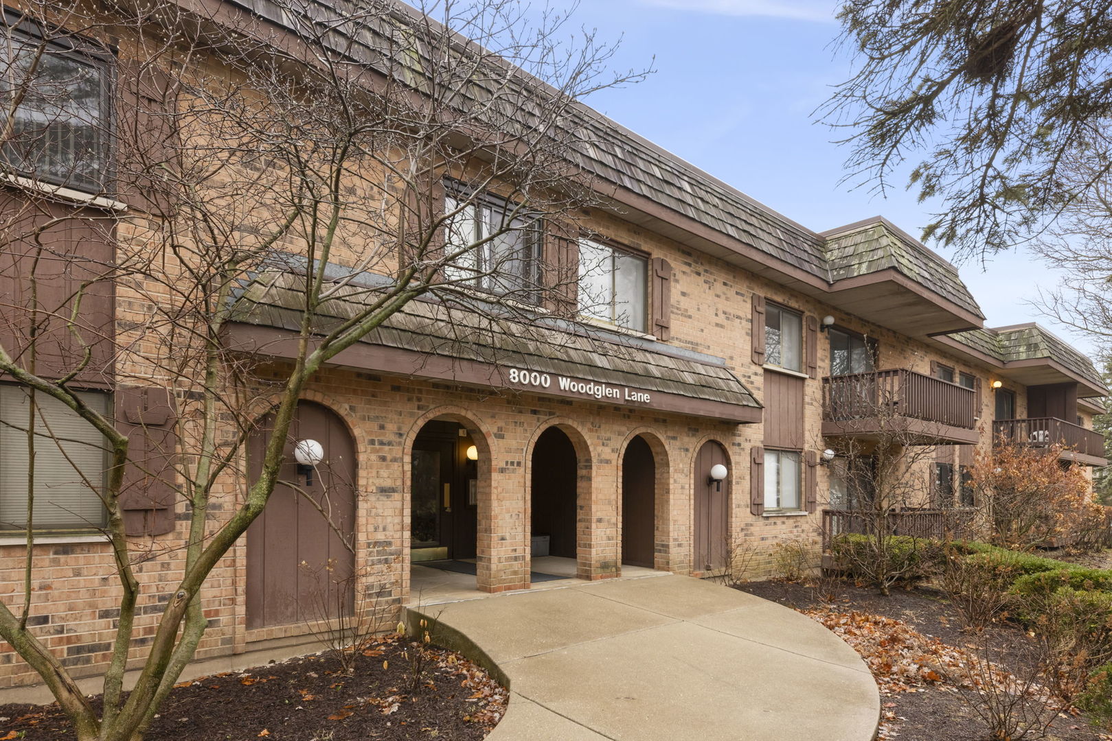 Brick residential building with an arched entrance, balconies, and a curved walkway.