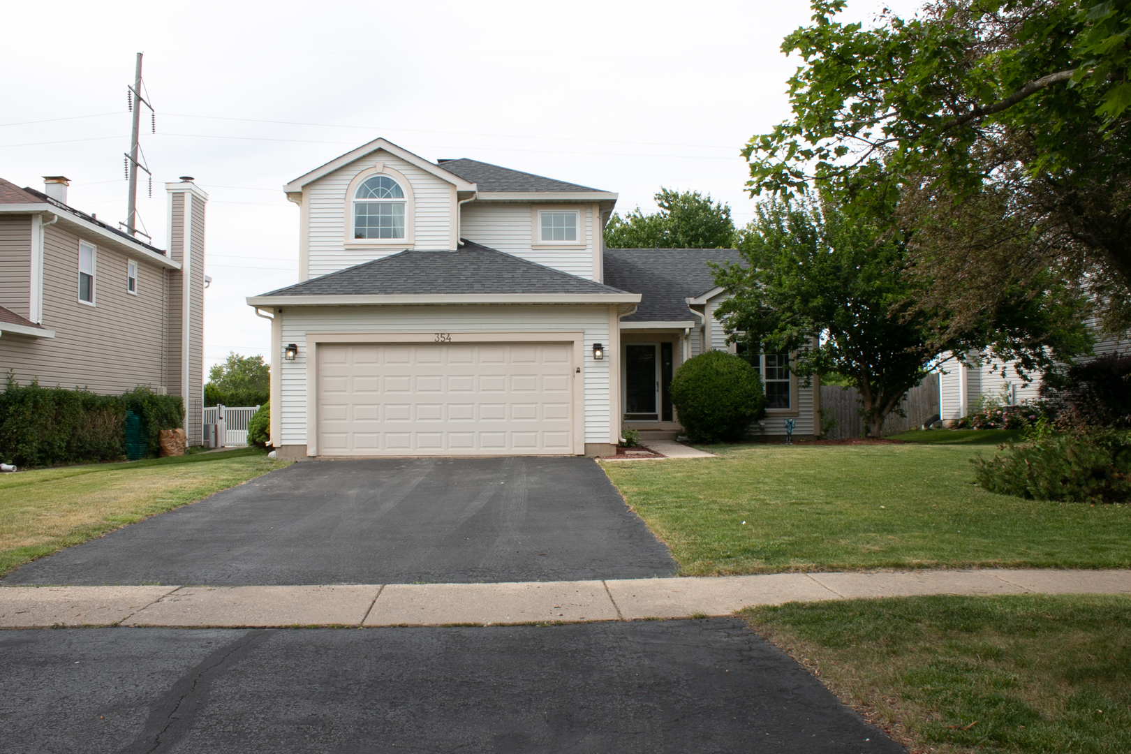 House at 354 with a double garage, wide driveway, and mature tree in the front yard.
