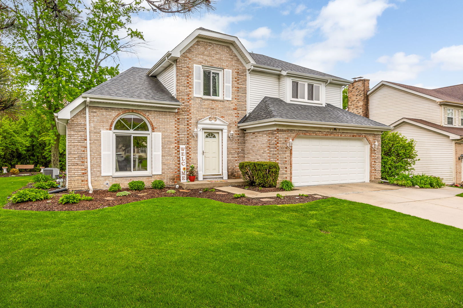 Two-story brick-and-siding home with an attached garage and landscaped front lawn.
