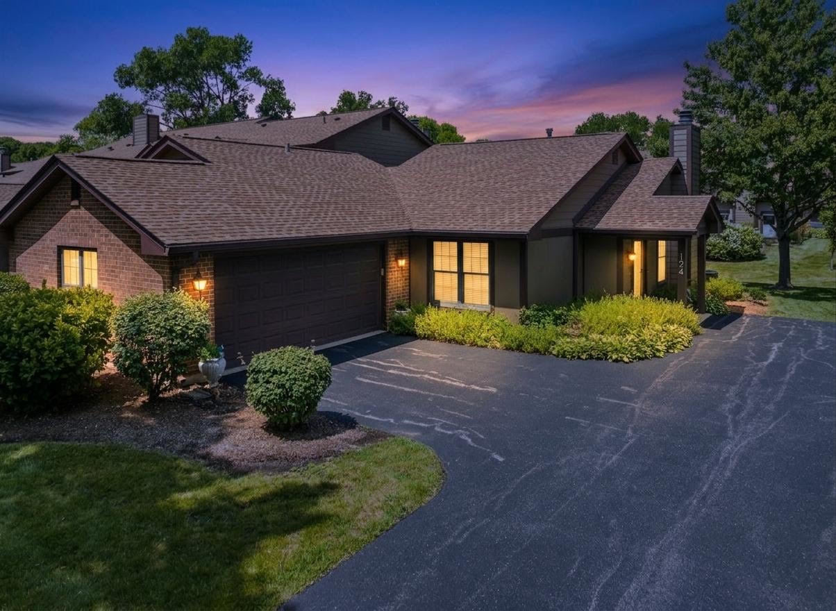 Single-story brick home with an attached garage and landscaped driveway at dusk.