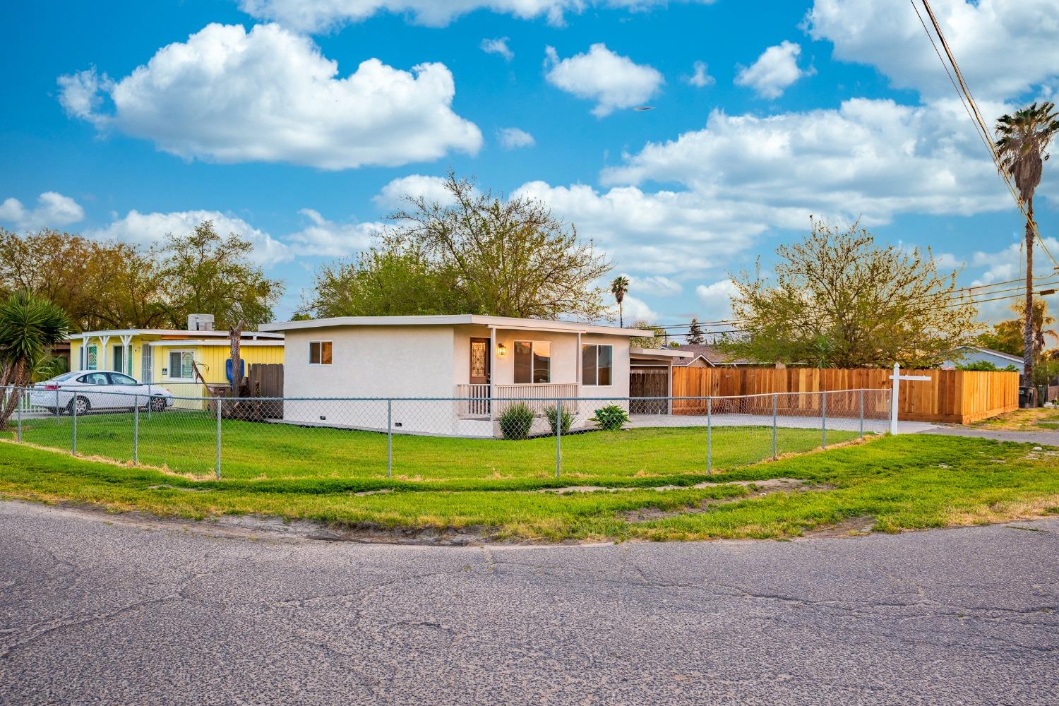 Single-story stucco home with a fenced lawn and wooden side fence.