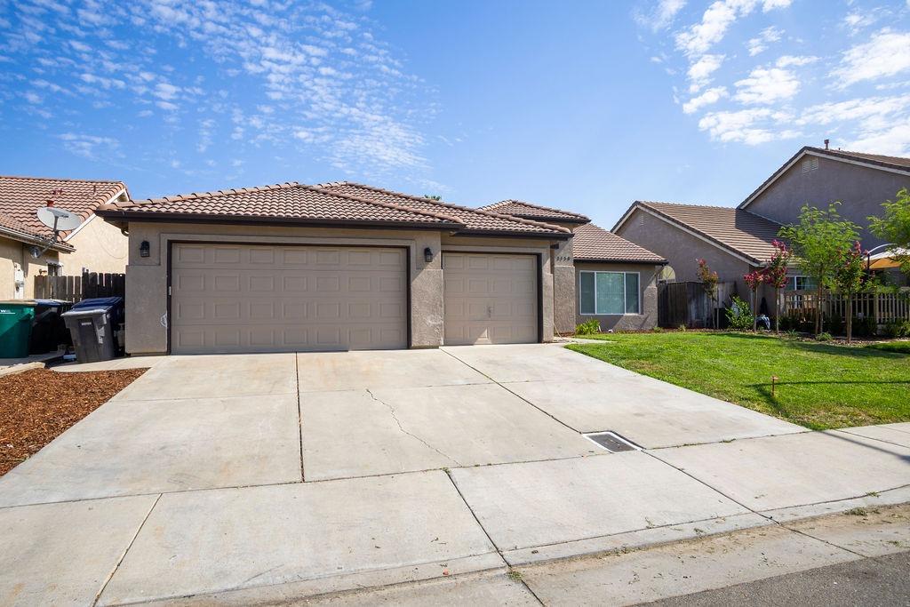 Single-story home with two garage doors, a wide driveway, and a green front lawn.
