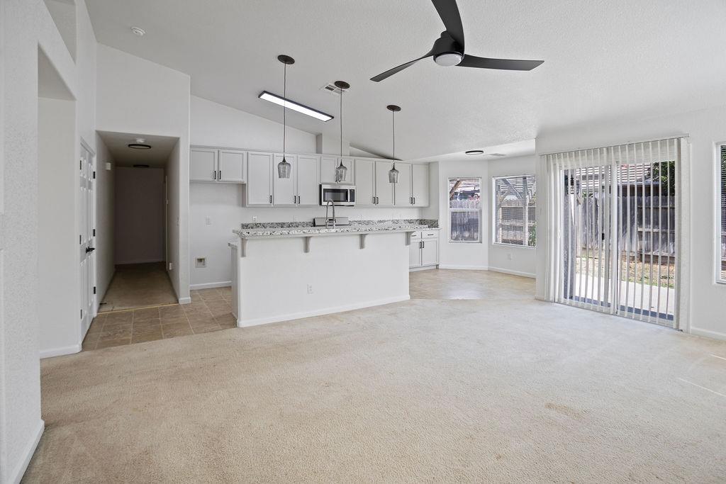 Open living room and kitchen with a granite-topped peninsula and sliding glass doors.