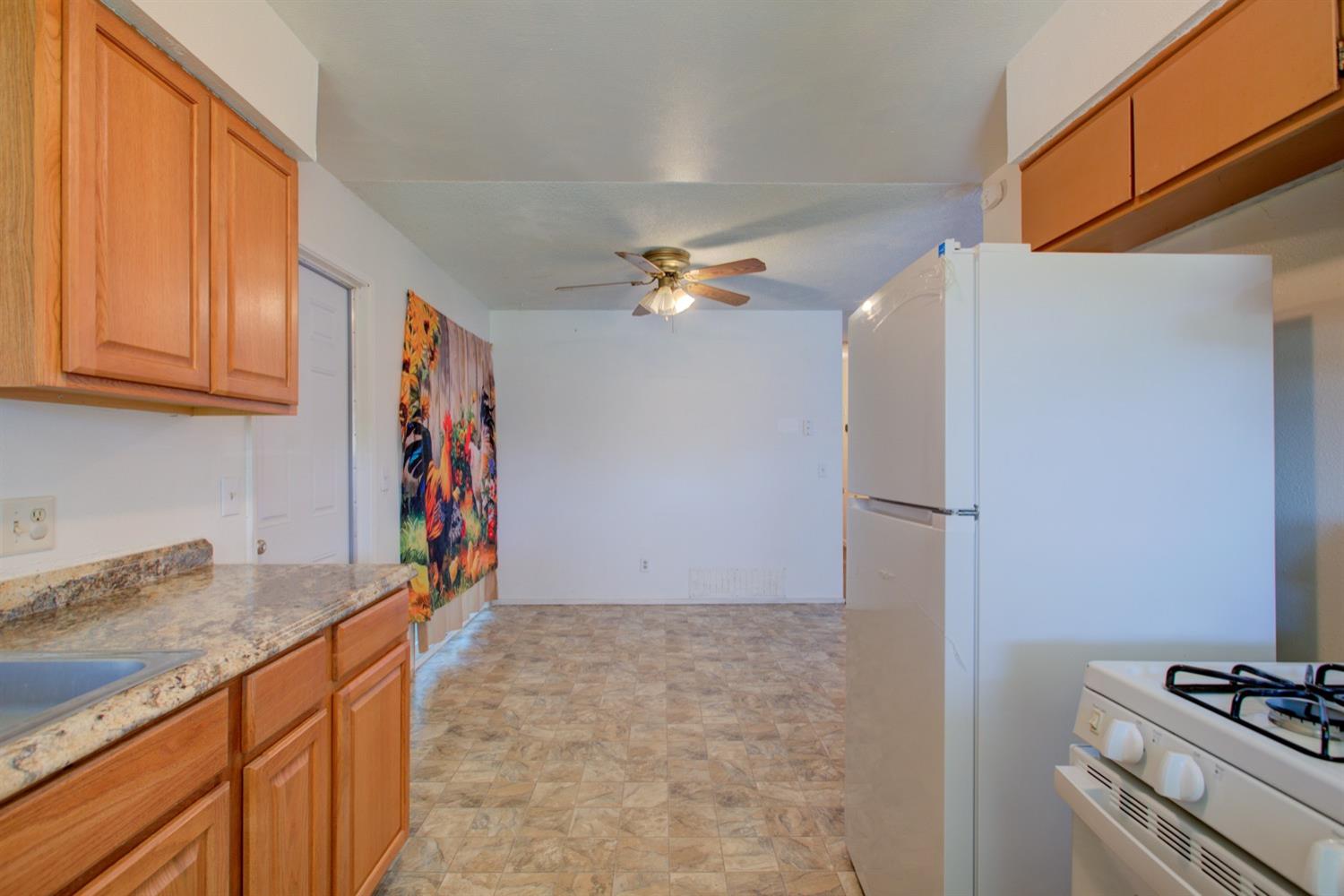 Kitchen with wood cabinets, patterned countertops, white appliances, and tile flooring.