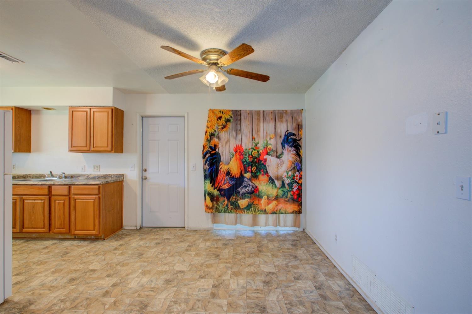 Kitchen and dining area with wood cabinets, patterned tile flooring, and rooster-print curtains.