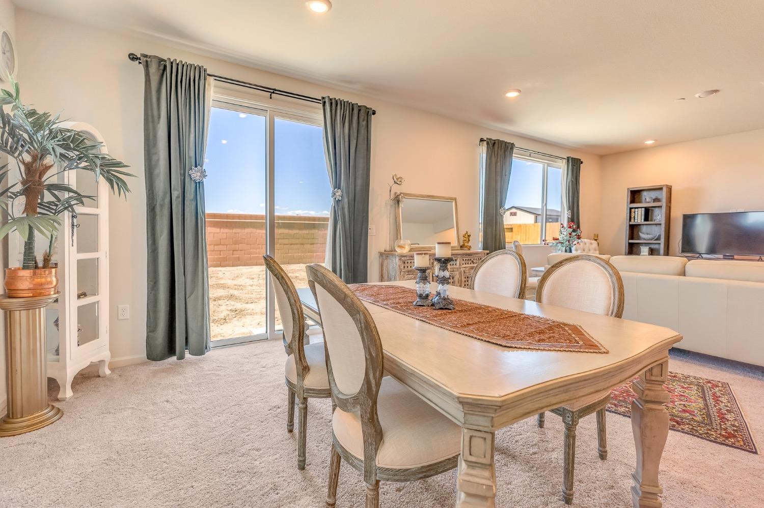 Dining room with a large table beside sliding glass doors overlooking a fenced backyard.