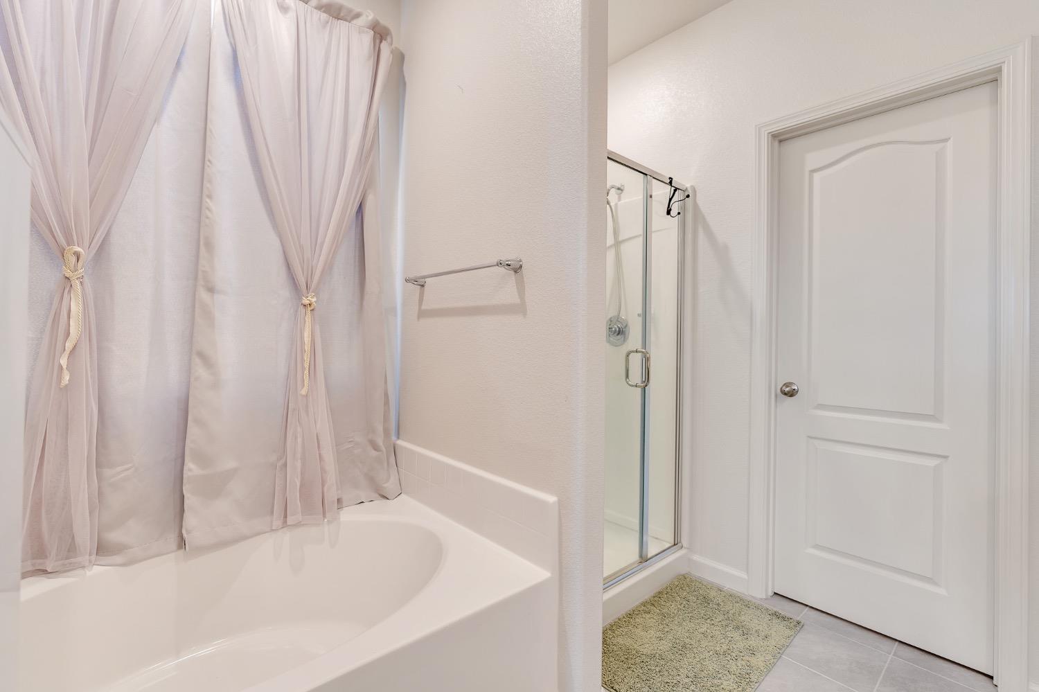 Bathroom with a curtained bathtub beside a glass shower and gray tile floor.