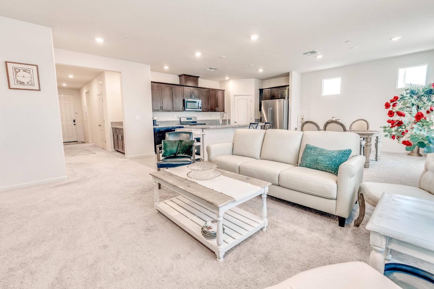 Open-plan living room with a white sofa, coffee table, and dark-cabinet kitchen.