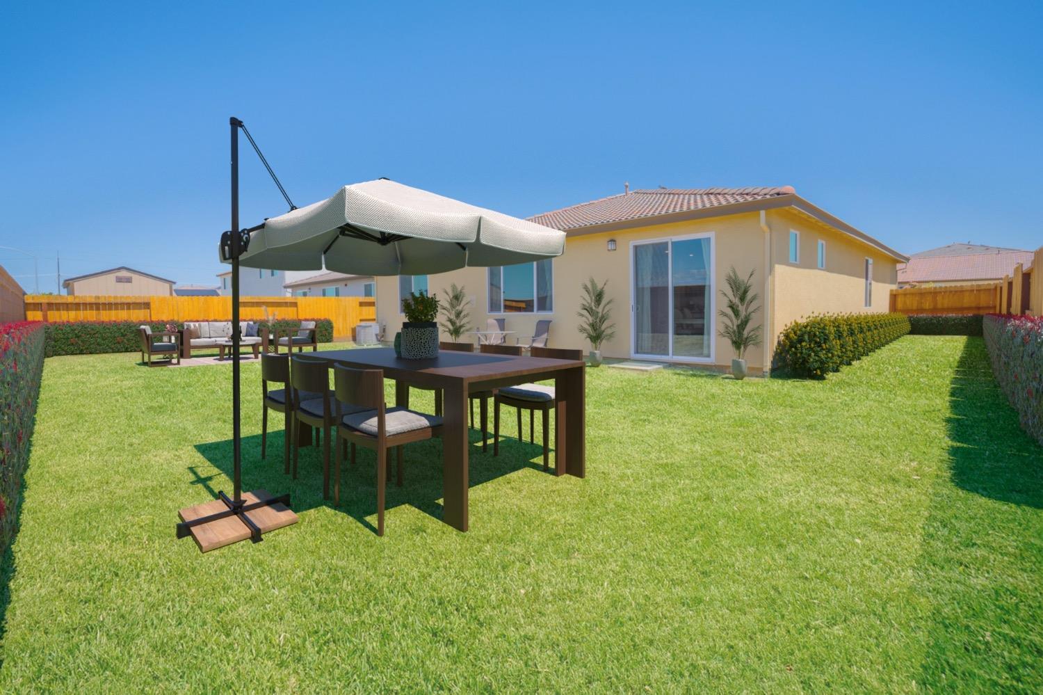 Backyard with a wide lawn and umbrella-shaded patio dining set beside a single-story home.