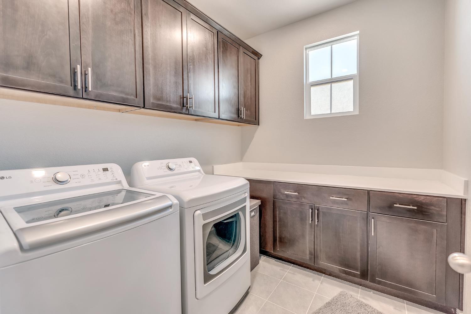 Laundry room with washer and dryer, dark wood cabinets, and a long folding counter.