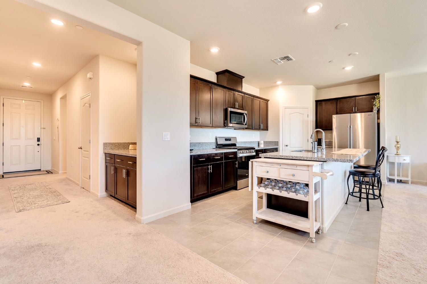 Open kitchen with dark wood cabinets, stainless steel appliances, and a large island with bar seating.