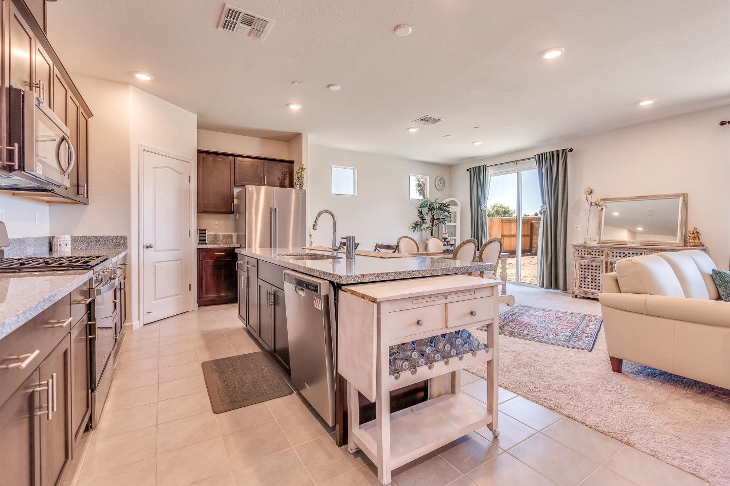 Open-plan kitchen with dark wood cabinets, stainless steel appliances, and a large granite-topped island.