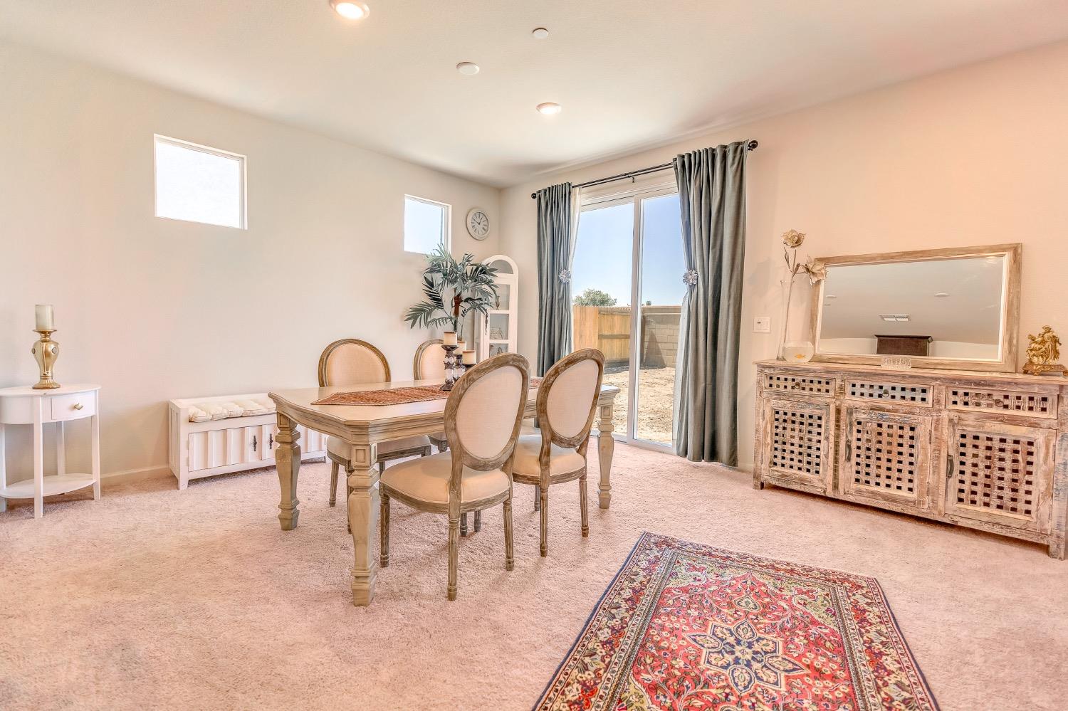 Dining room with a wood table, carved sideboard, and sliding glass doors to the backyard.
