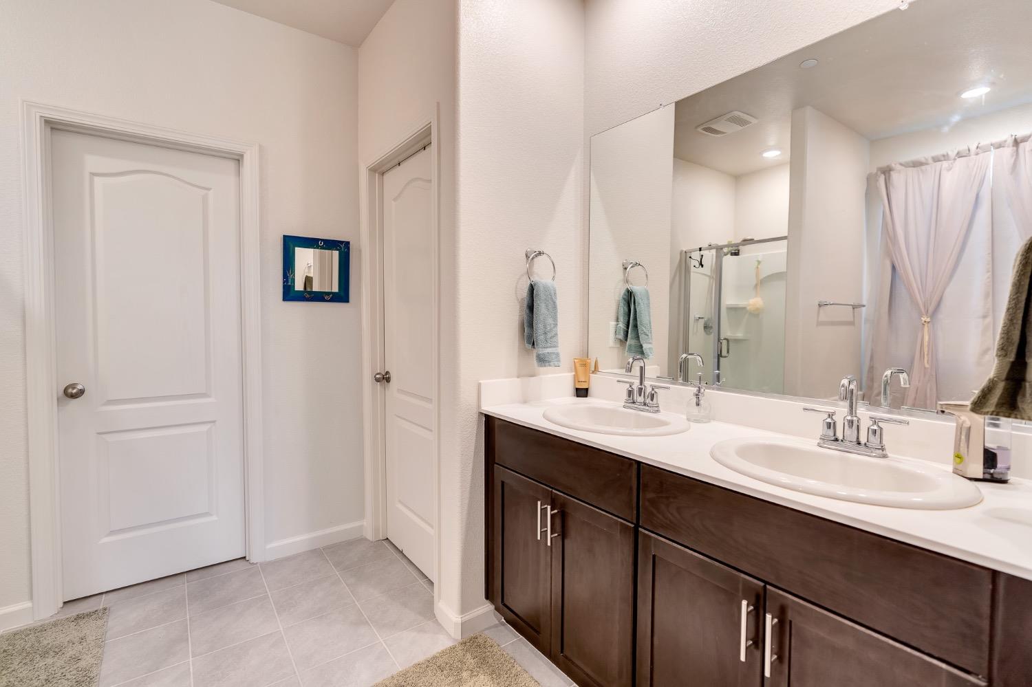 Bathroom with a double-sink vanity, dark wood cabinets, and a glass-enclosed shower.