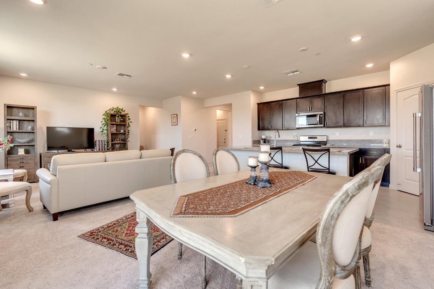 Open-plan living and dining area with a pale table, light sofa, and dark wood kitchen cabinets.