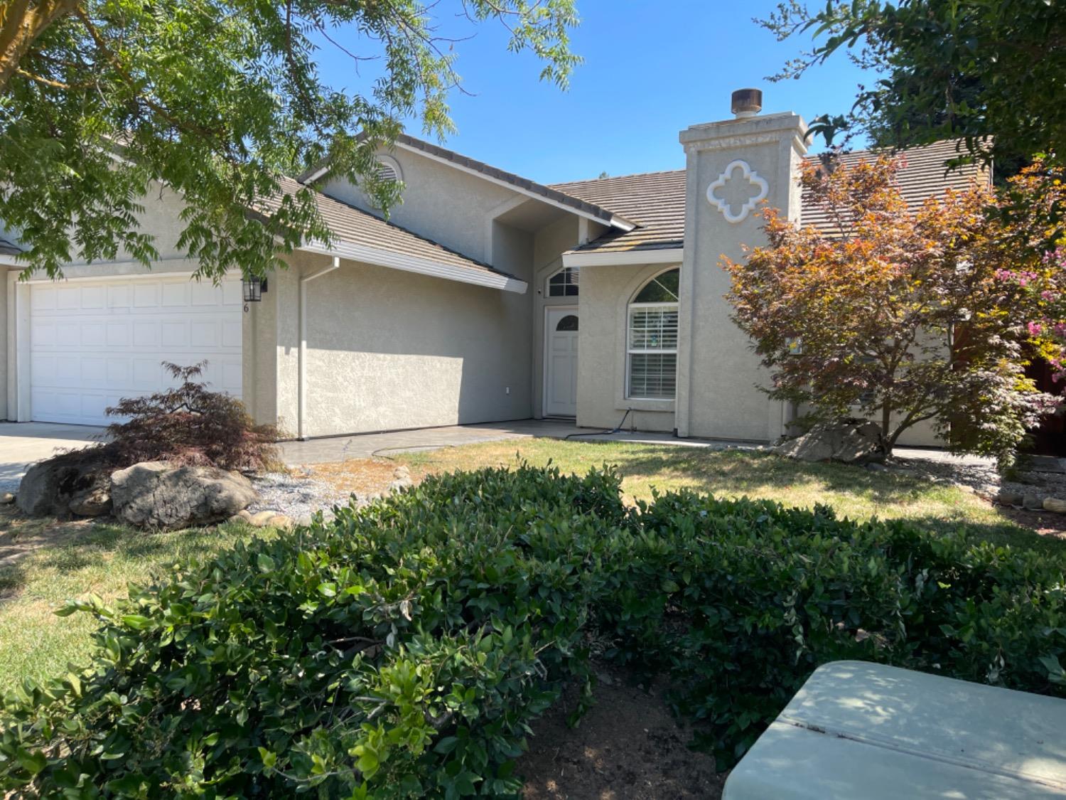 Stucco home with an arched entry, decorative chimney, and landscaped front yard.