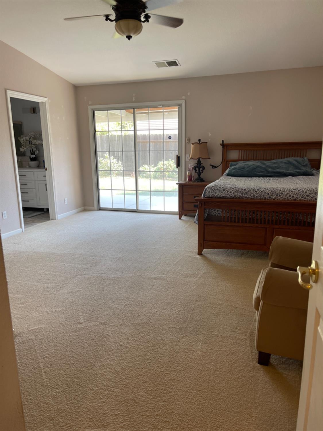 Furnished bedroom with a wooden bed and sliding glass doors to a fenced backyard.