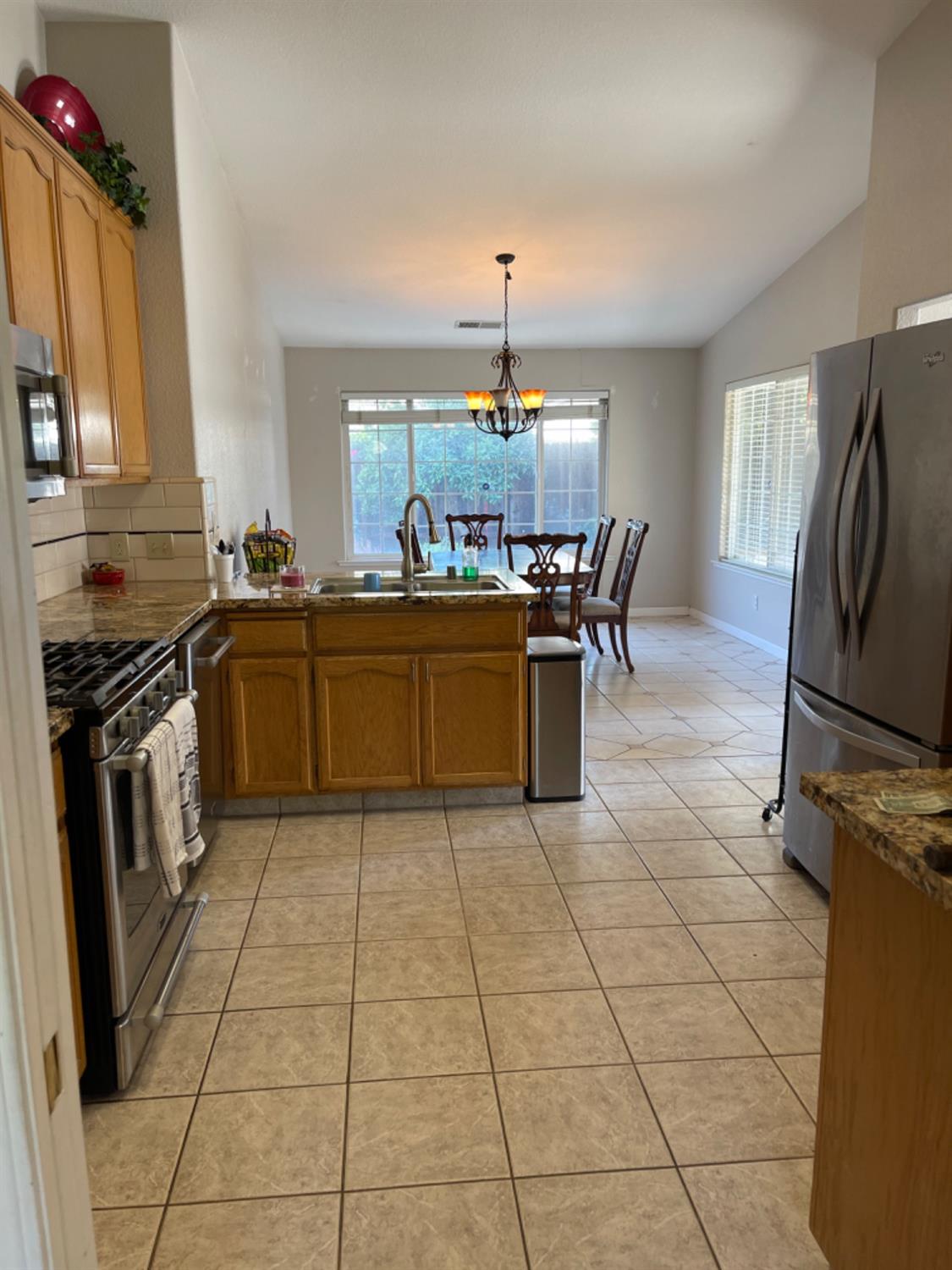 Kitchen with oak cabinets and granite counters opening to a dining area with large windows.