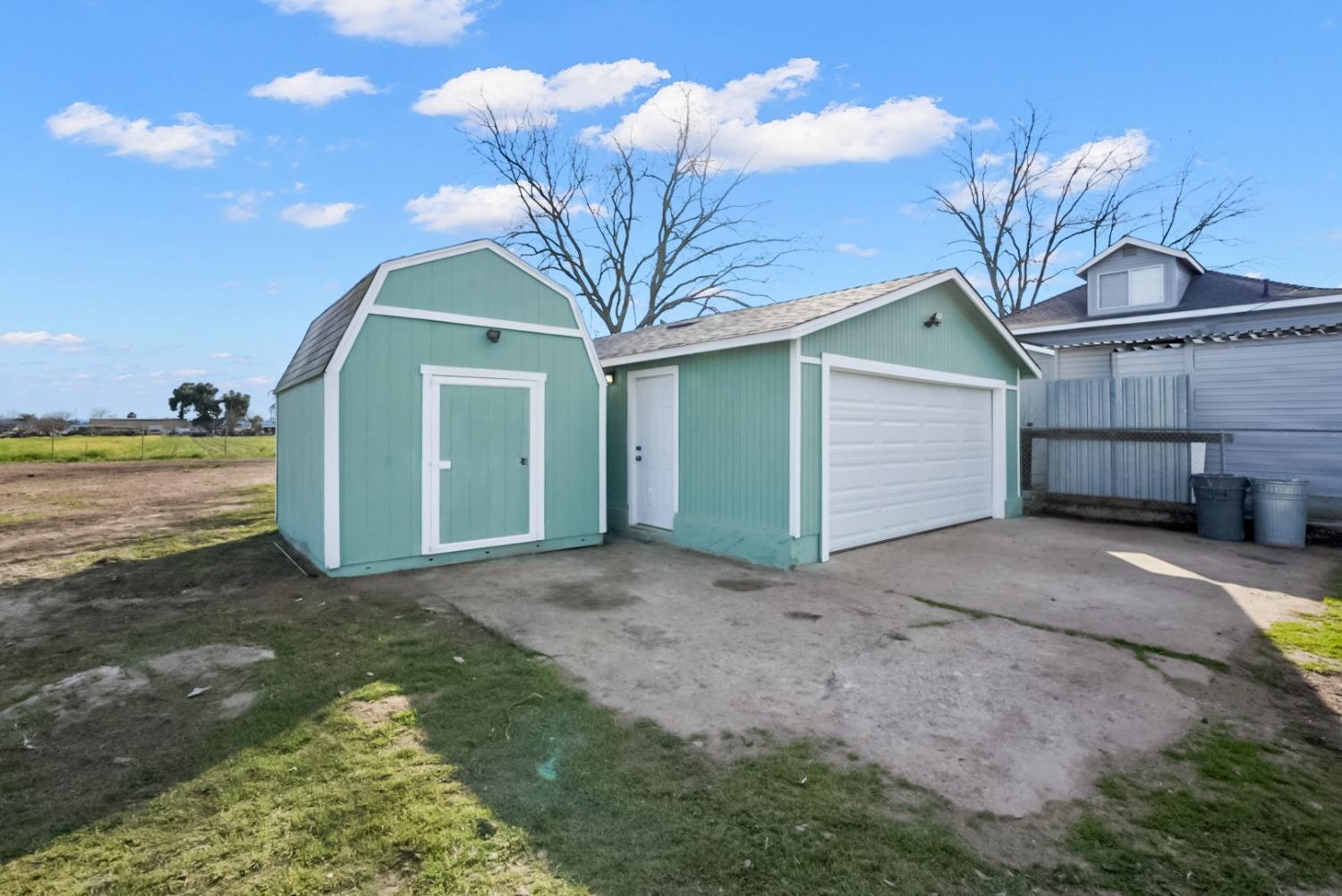 Mint-green detached garage and matching barn-style shed beside a concrete driveway.