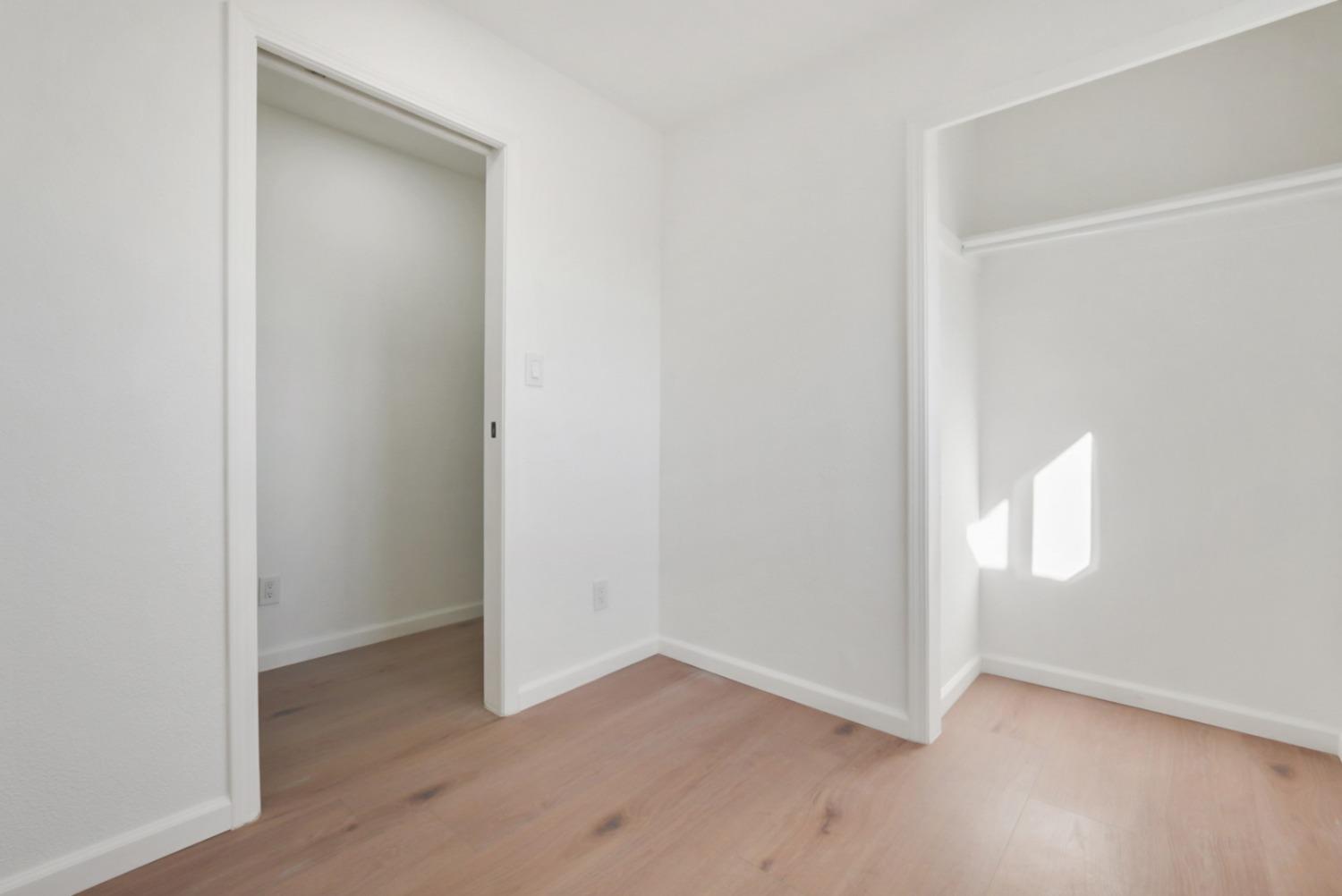 Empty bedroom with light wood floors and an open closet.